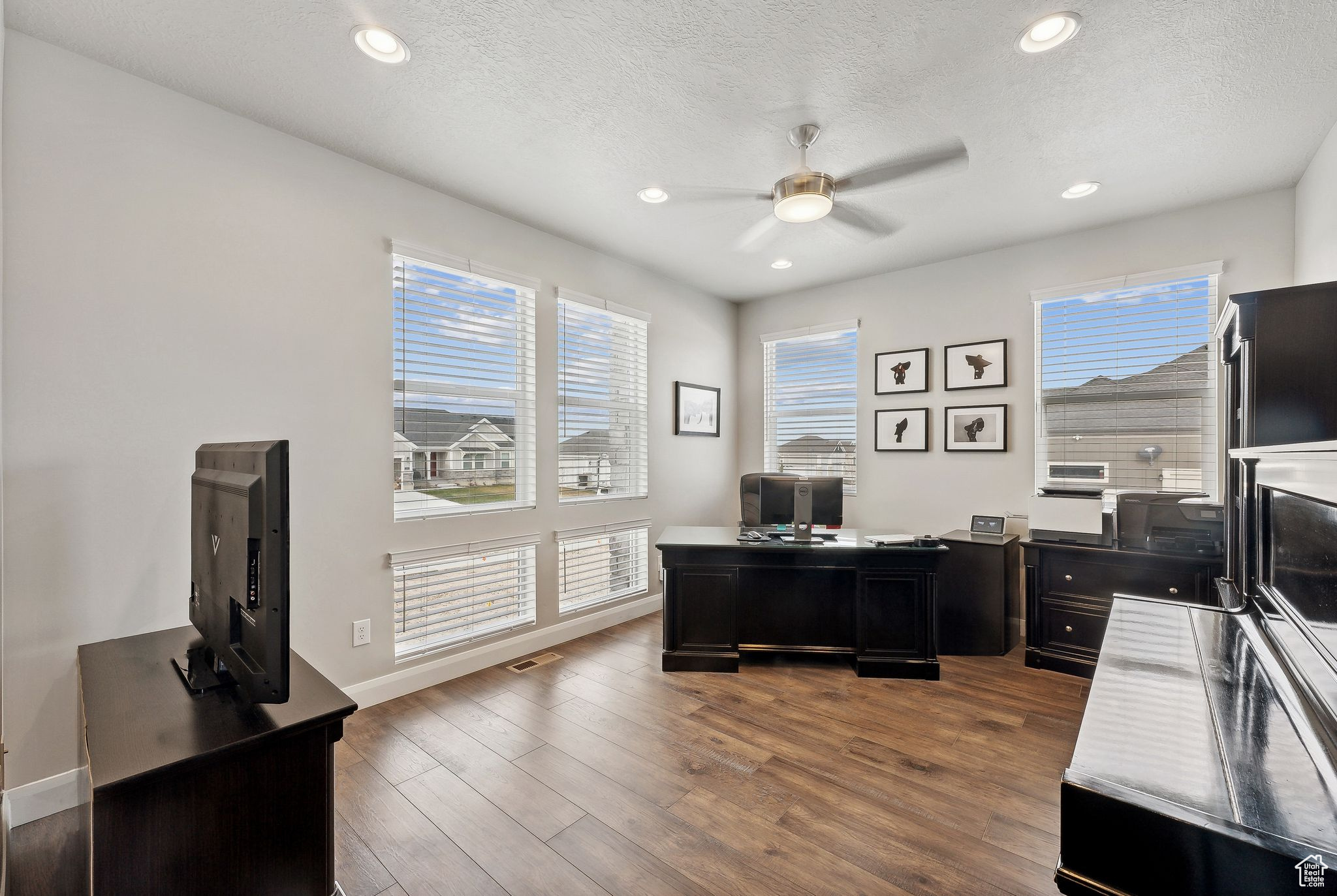 Home office with a textured ceiling, dark hardwood / wood-style flooring, and ceiling fan