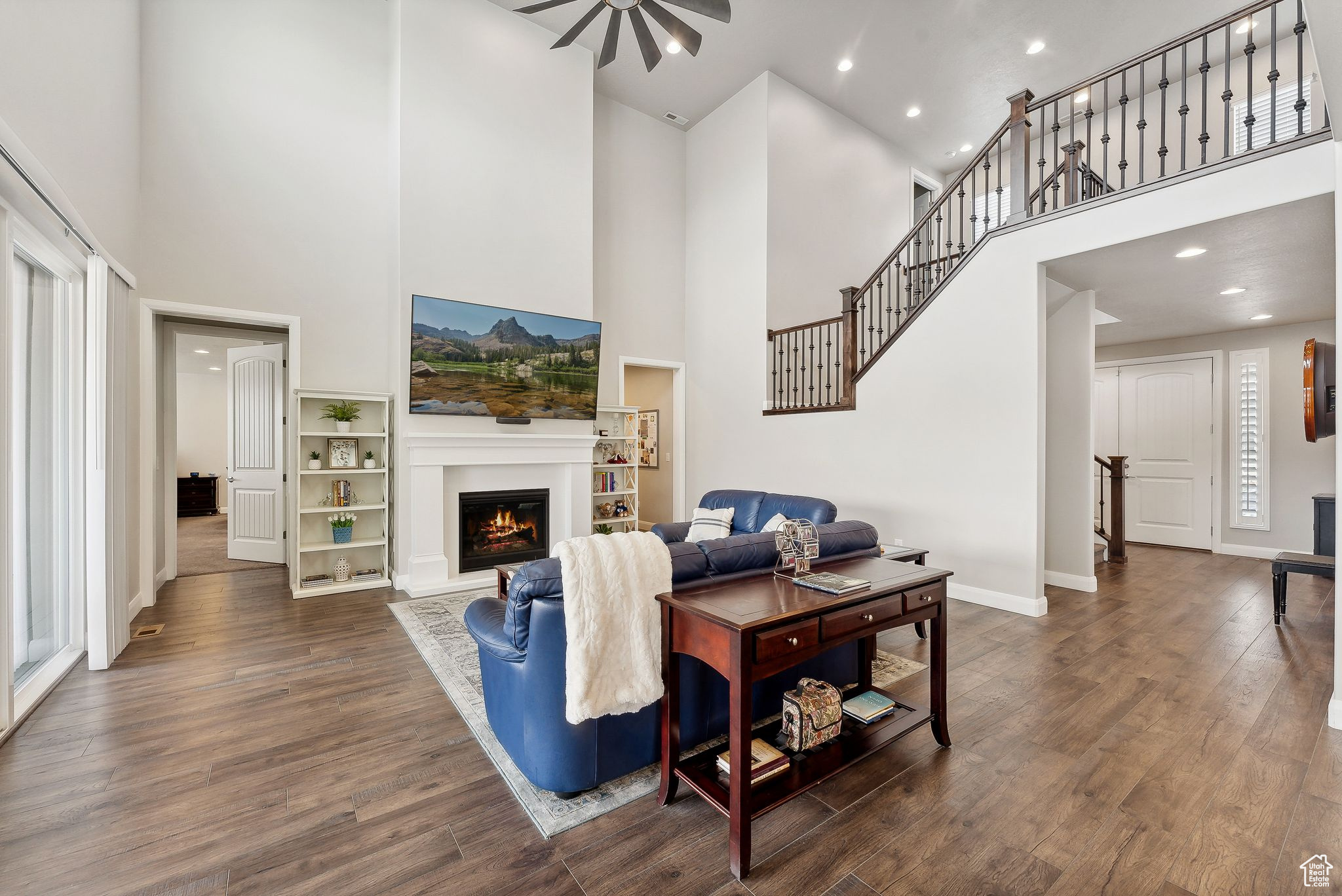 Living room with ceiling fan, dark wood-type flooring, and a high ceiling