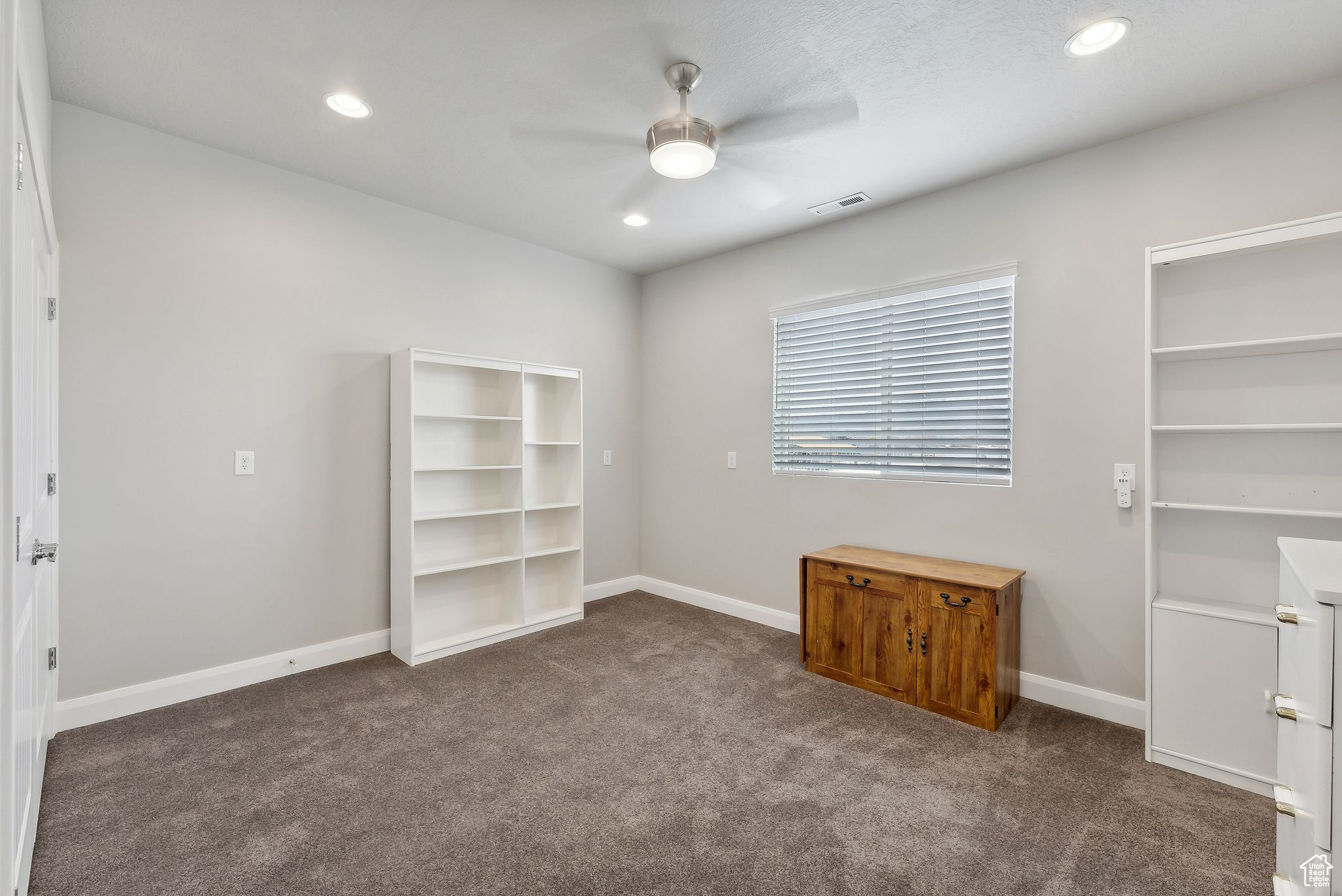 Unfurnished bedroom with dark carpet and ceiling fan