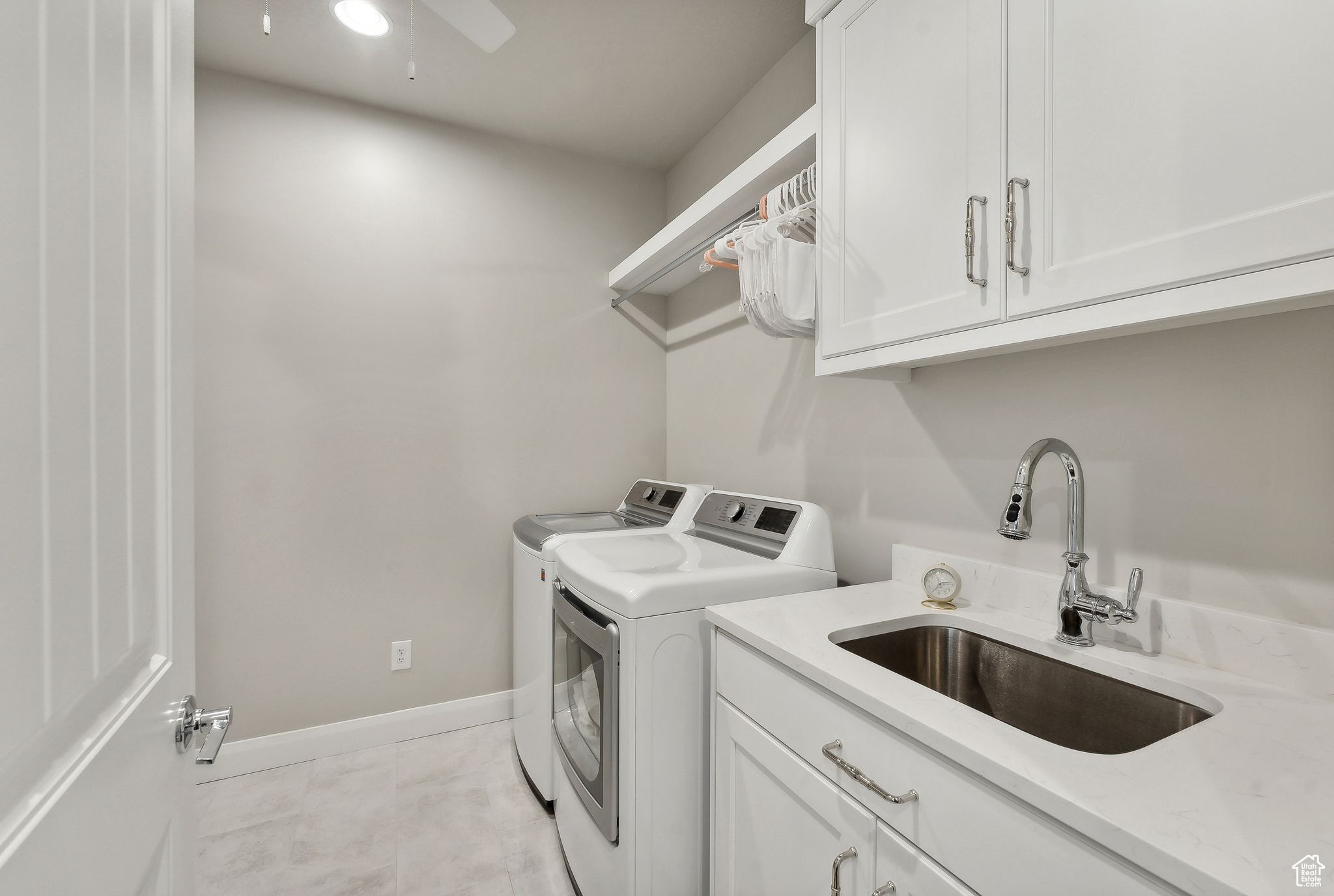 Clothes washing area with cabinets, sink, ceiling fan, independent washer and dryer, and light tile patterned floors