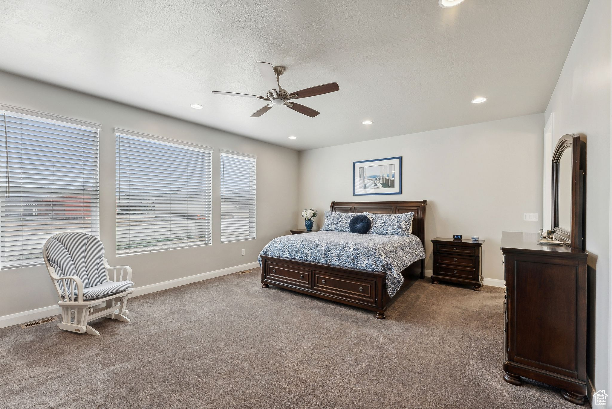 Carpeted bedroom featuring a textured ceiling and ceiling fan