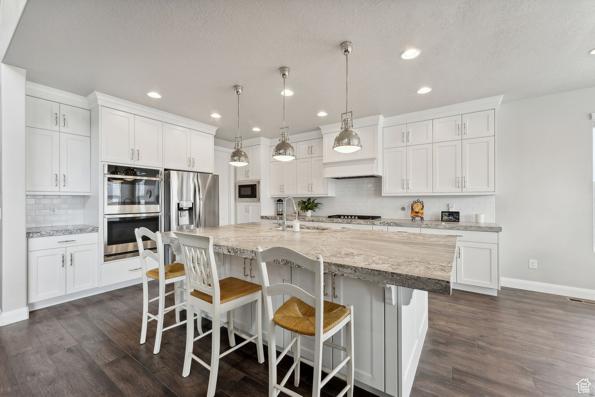 Kitchen with pendant lighting, dark wood-type flooring, sink, white cabinetry, and stainless steel appliances