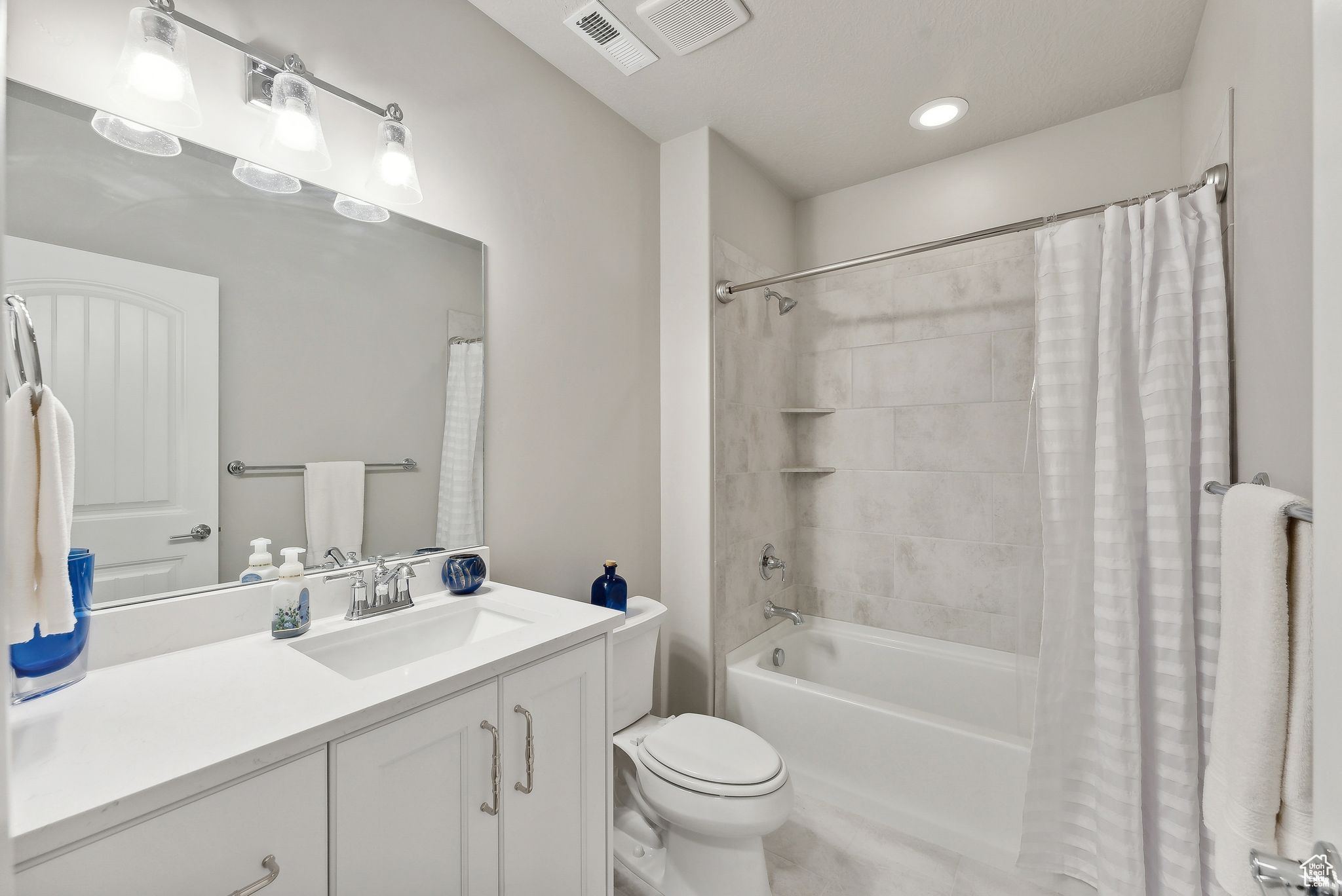 Full bathroom featuring vanity, toilet, and shower / bathtub combination with curtain