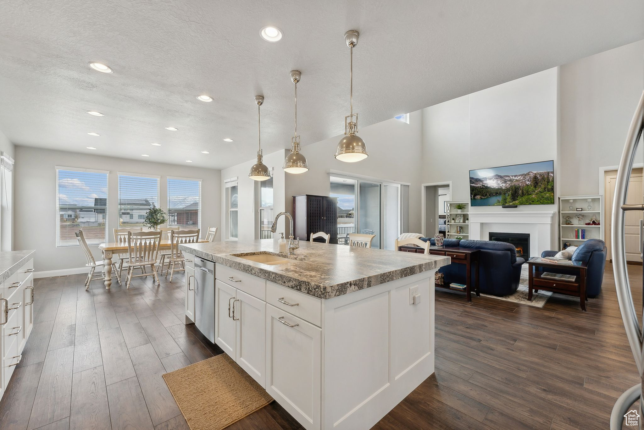 Kitchen with a kitchen island with sink, dark wood-type flooring, sink, pendant lighting, and white cabinets