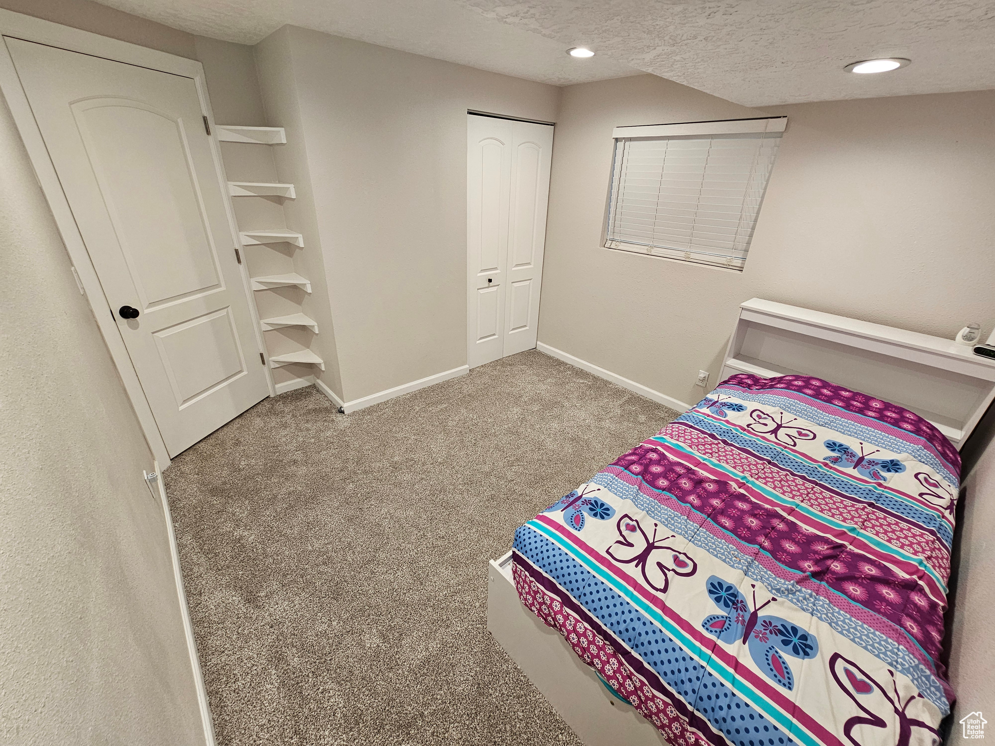 Carpeted bedroom featuring a textured ceiling and a closet