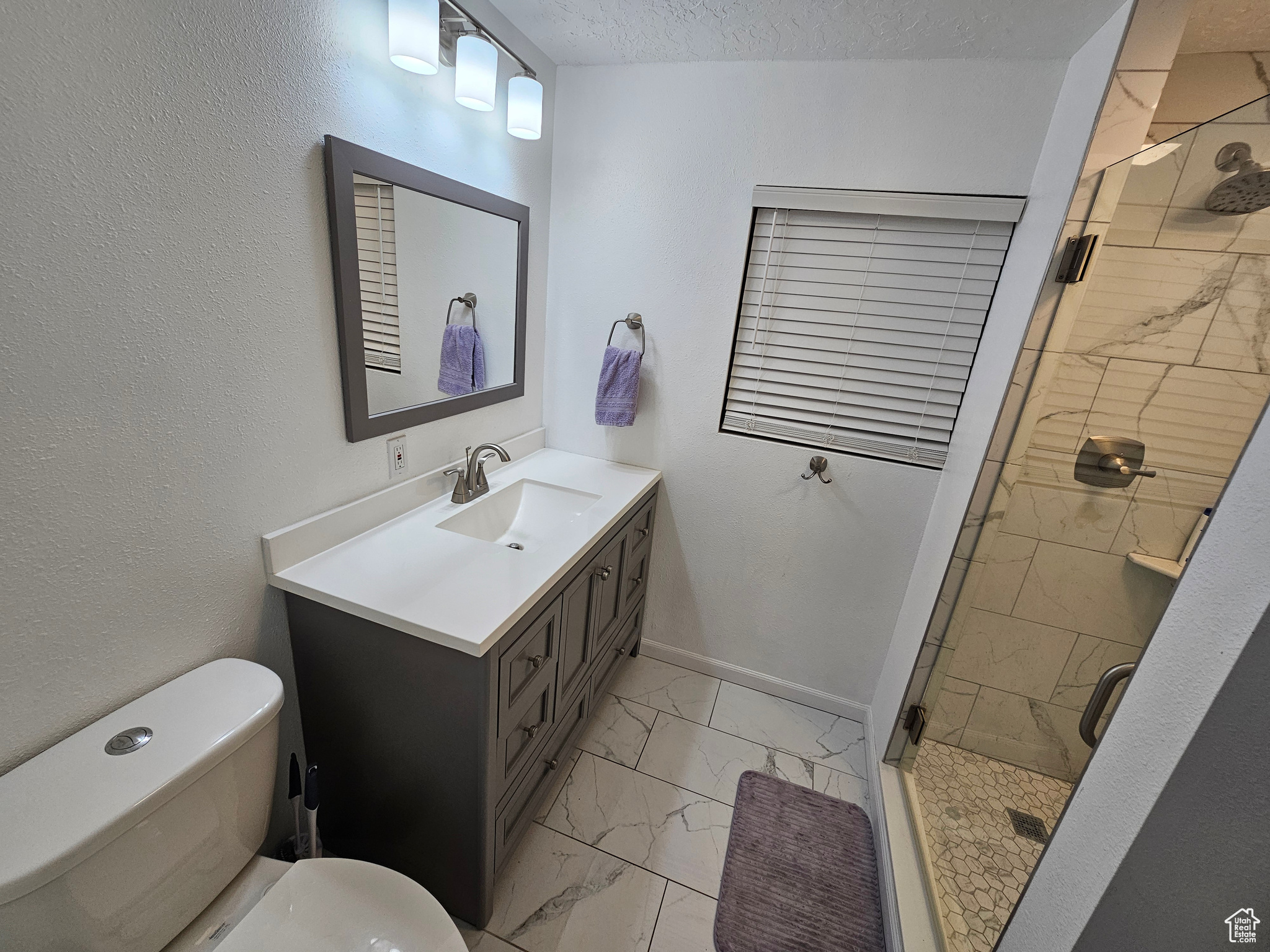 Bathroom with toilet, vanity, a textured ceiling, and walk in shower