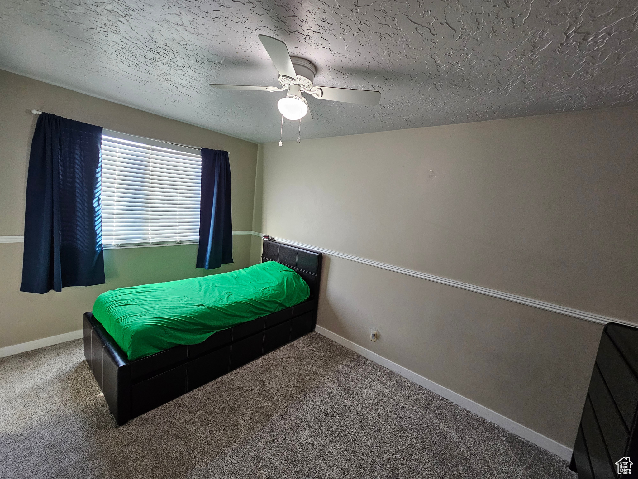 Bedroom featuring ceiling fan, carpet, and a textured ceiling