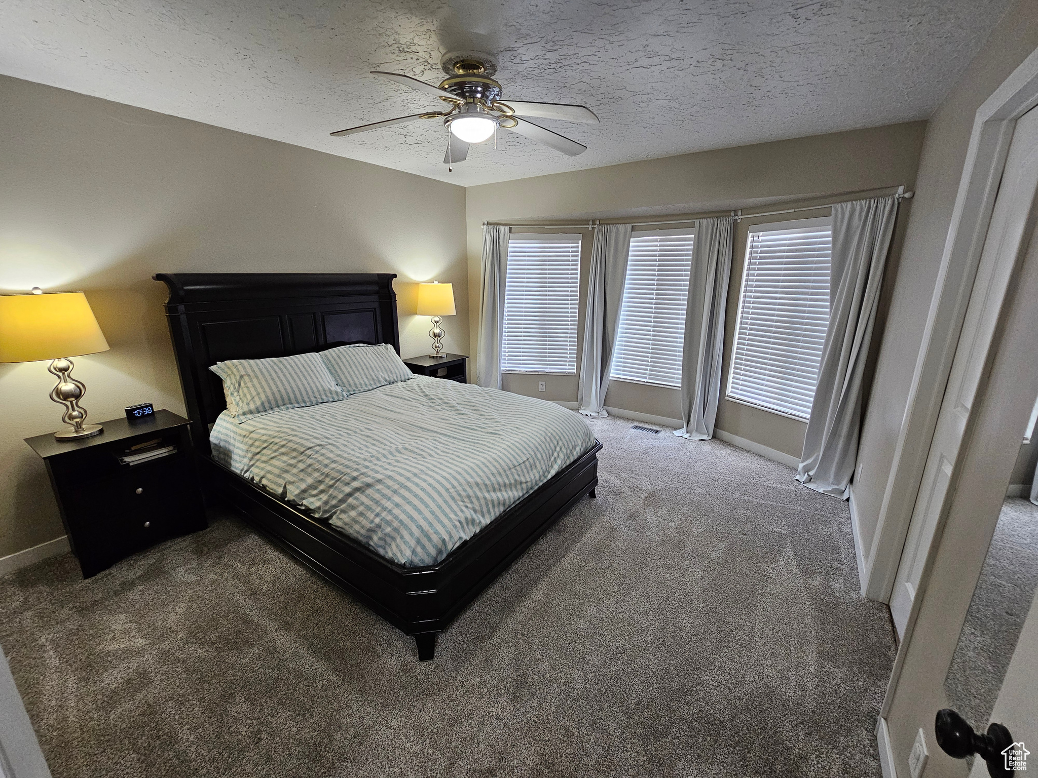 Carpeted bedroom with ceiling fan and a textured ceiling