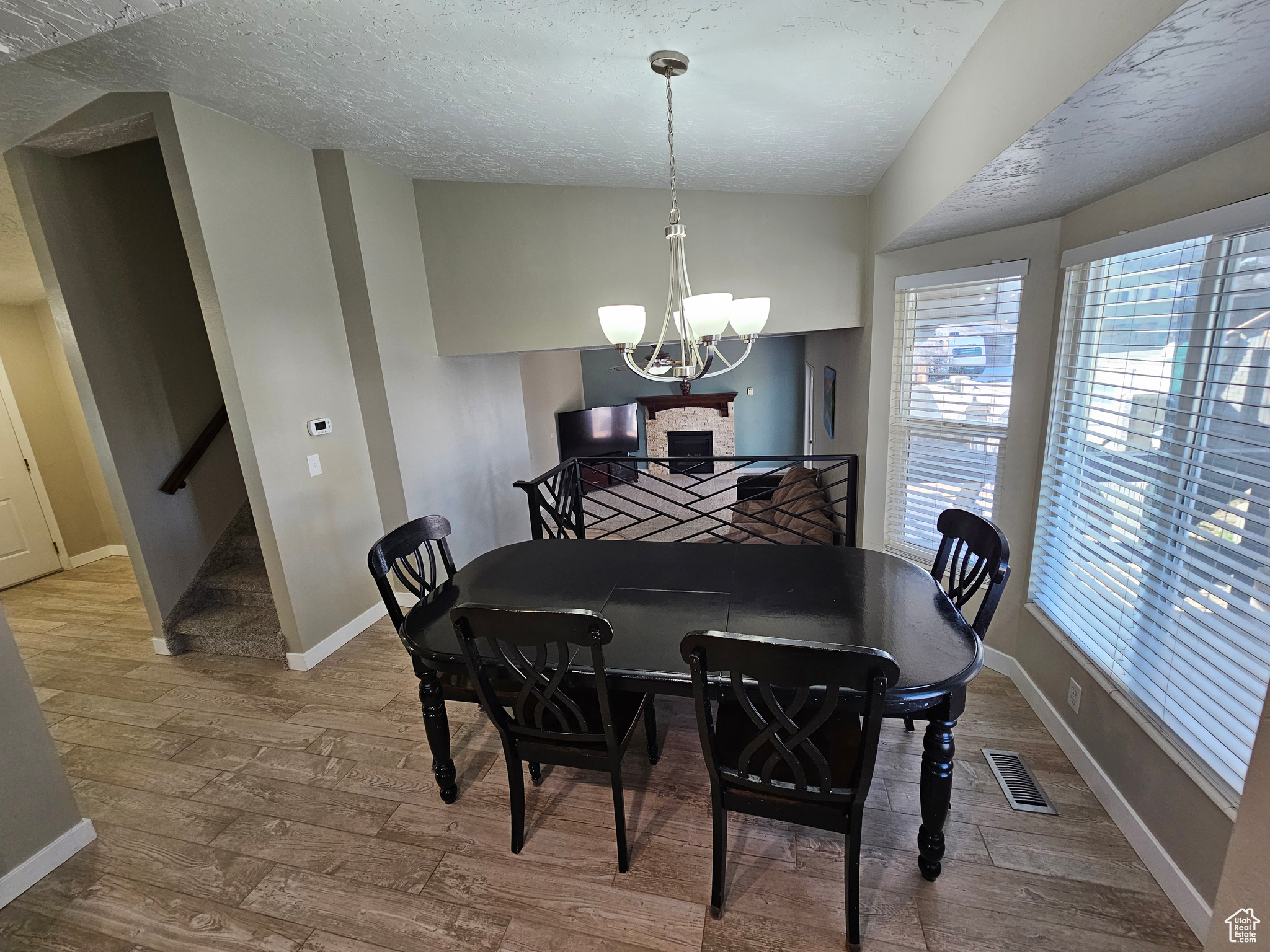 Dining area with hardwood / wood-style floors, a textured ceiling, and a notable chandelier