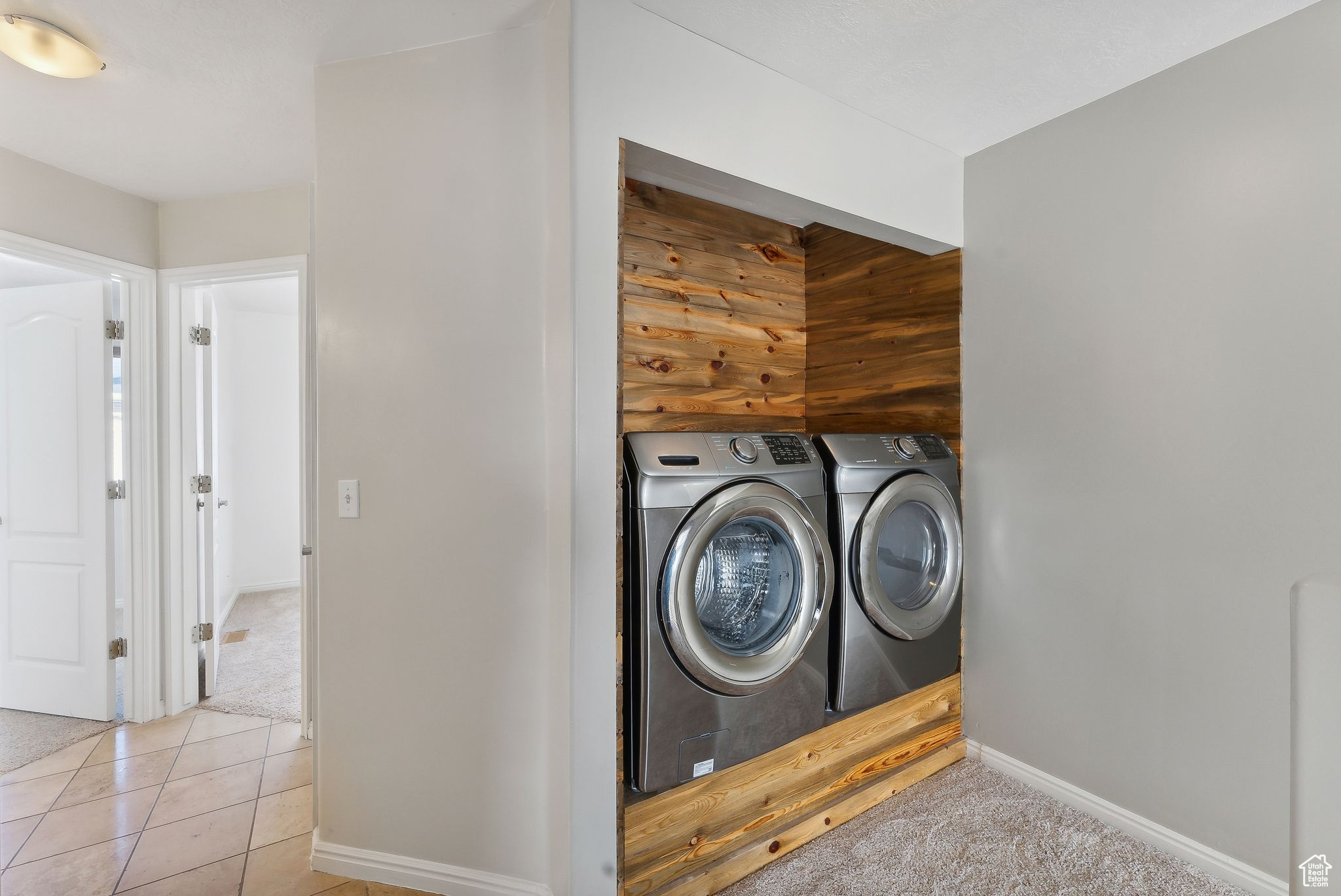 Clothes washing area featuring independent washer and dryer and light tile patterned floors