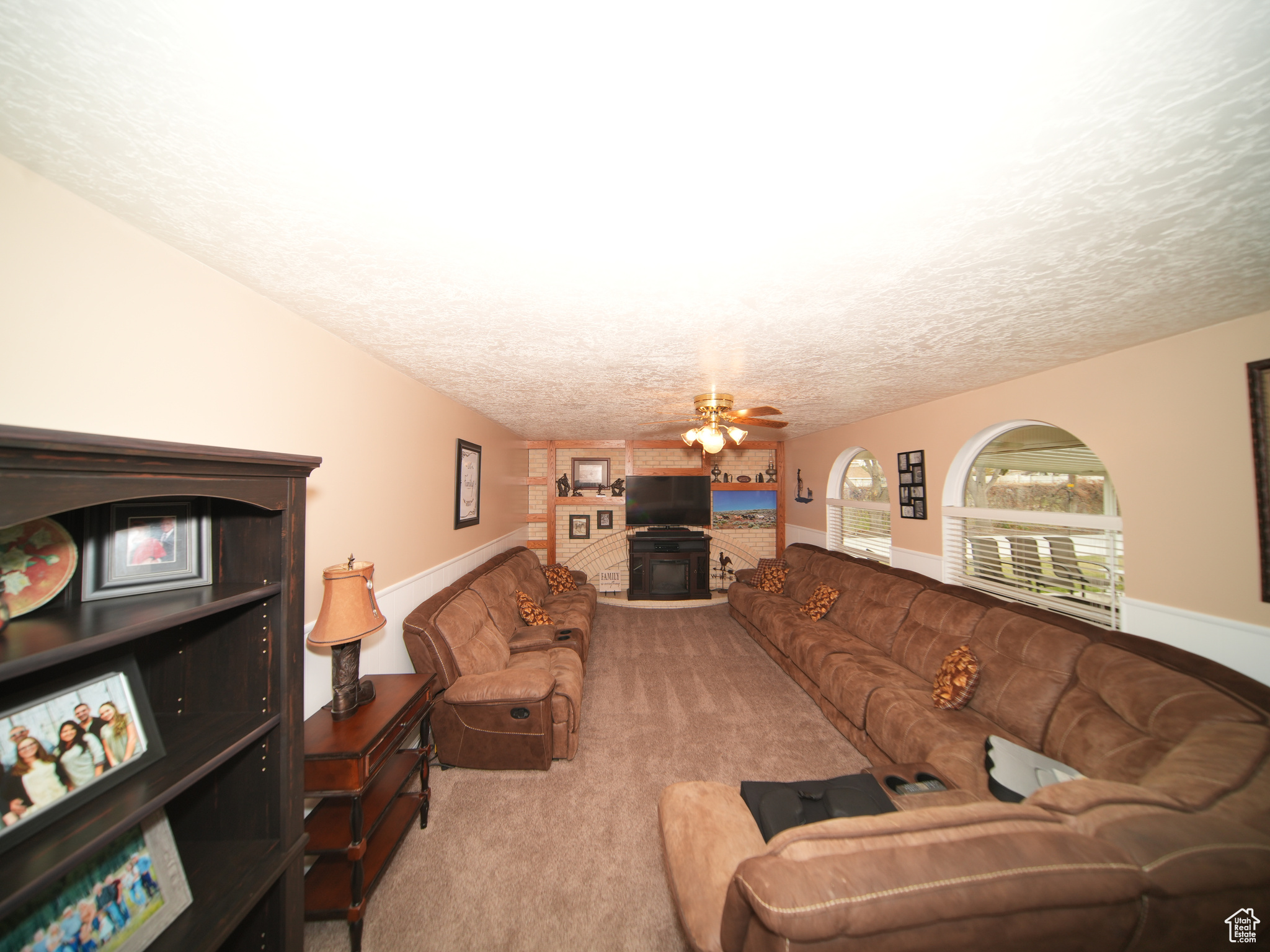 Living room featuring ceiling fan, light colored carpet, lofted ceiling, and a textured ceiling