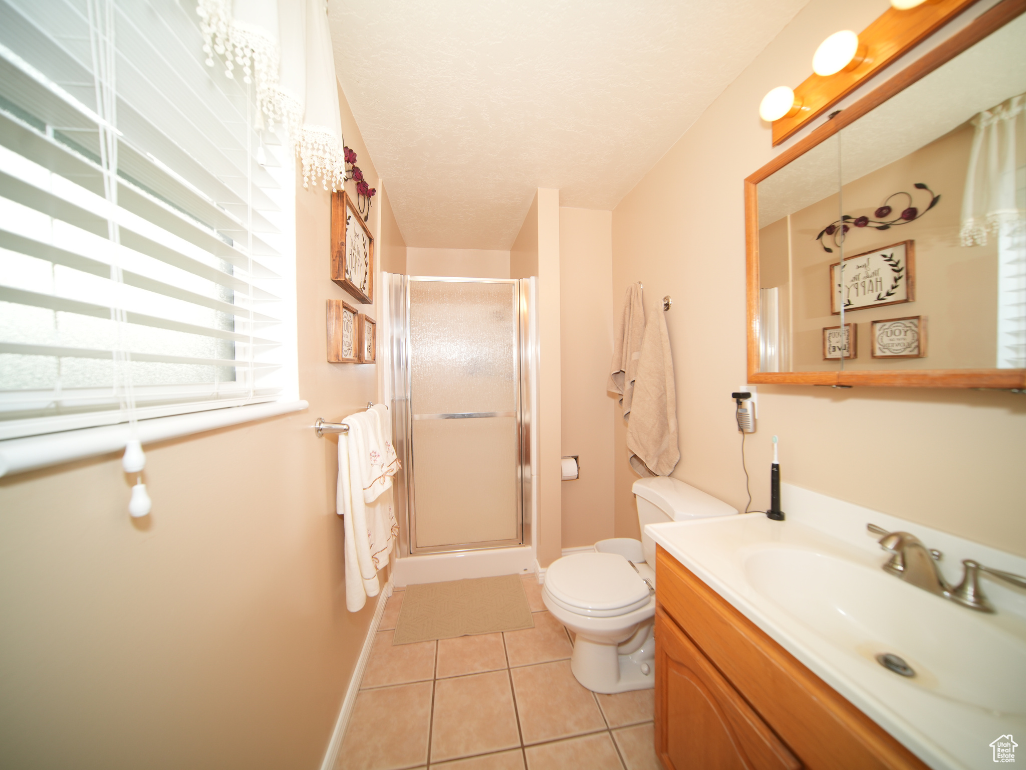 Bathroom featuring tile patterned flooring, vanity, toilet, and walk in shower