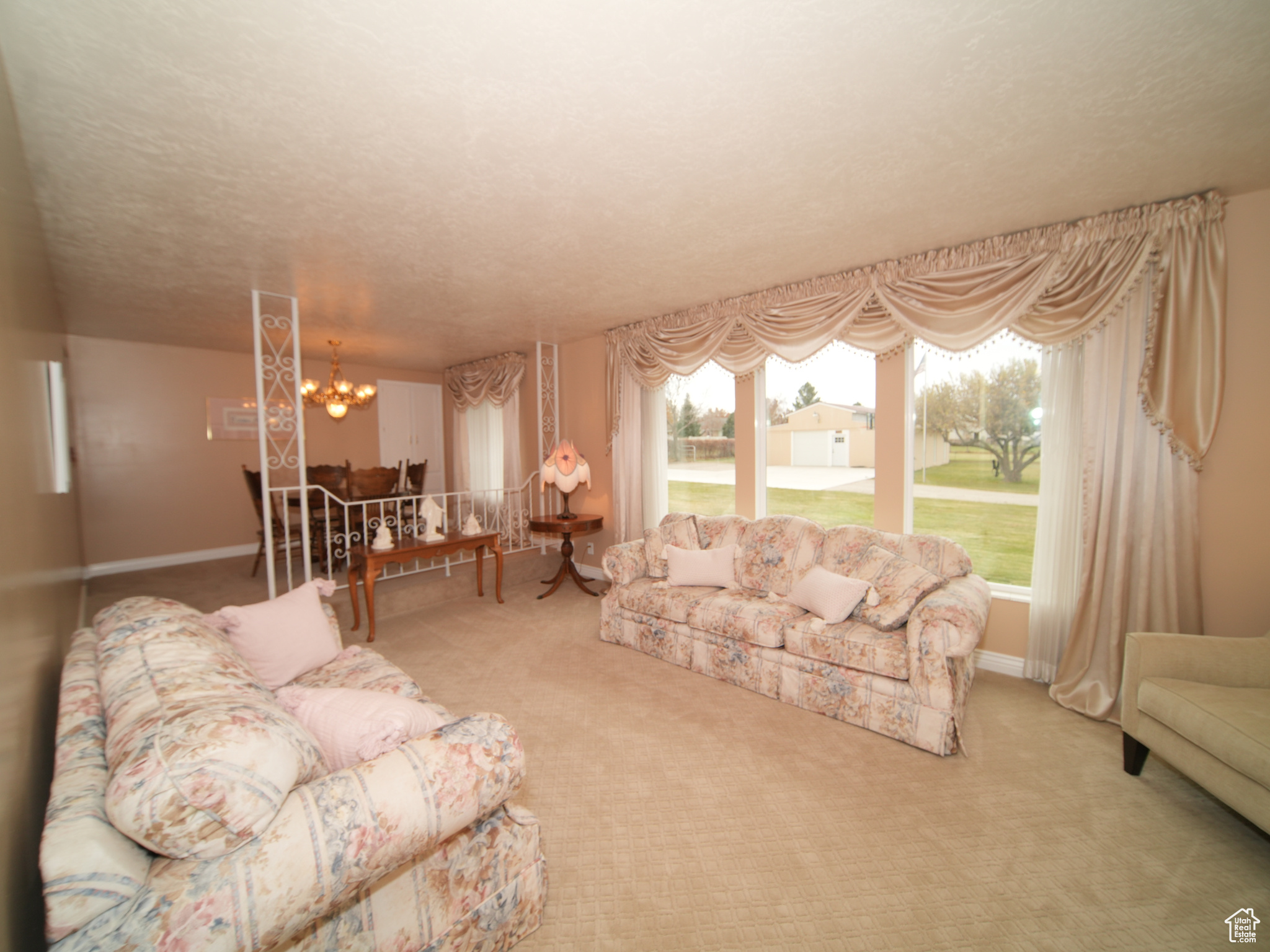 Carpeted living room with a textured ceiling and a notable chandelier