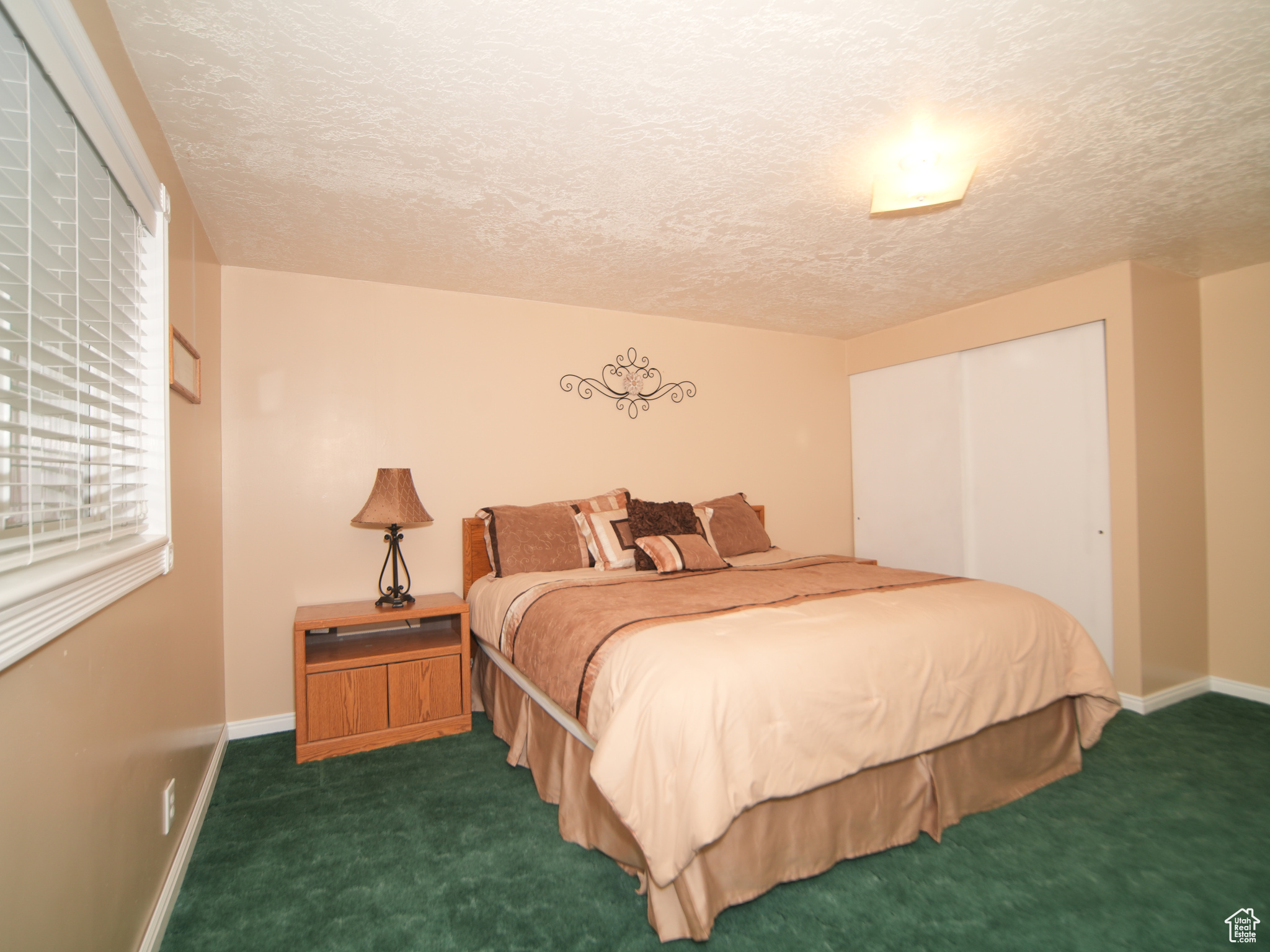 Bedroom with dark colored carpet and a textured ceiling