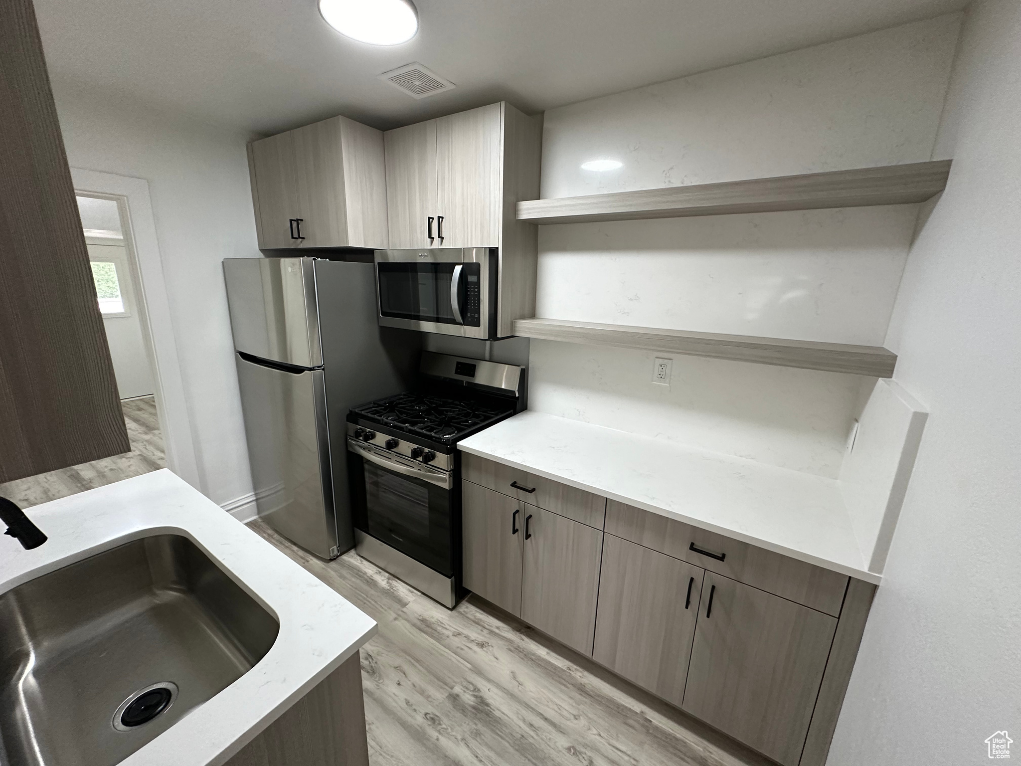 Kitchen with stainless steel appliances, light hardwood / wood-style flooring, and sink