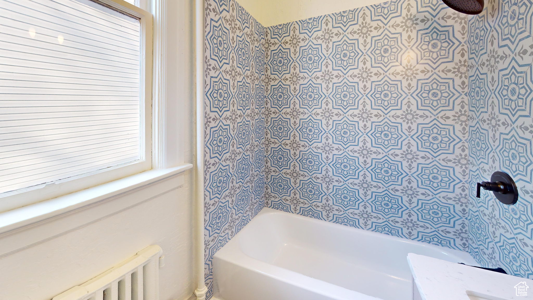 Bathroom with radiator heating unit and tiled shower / bath combo