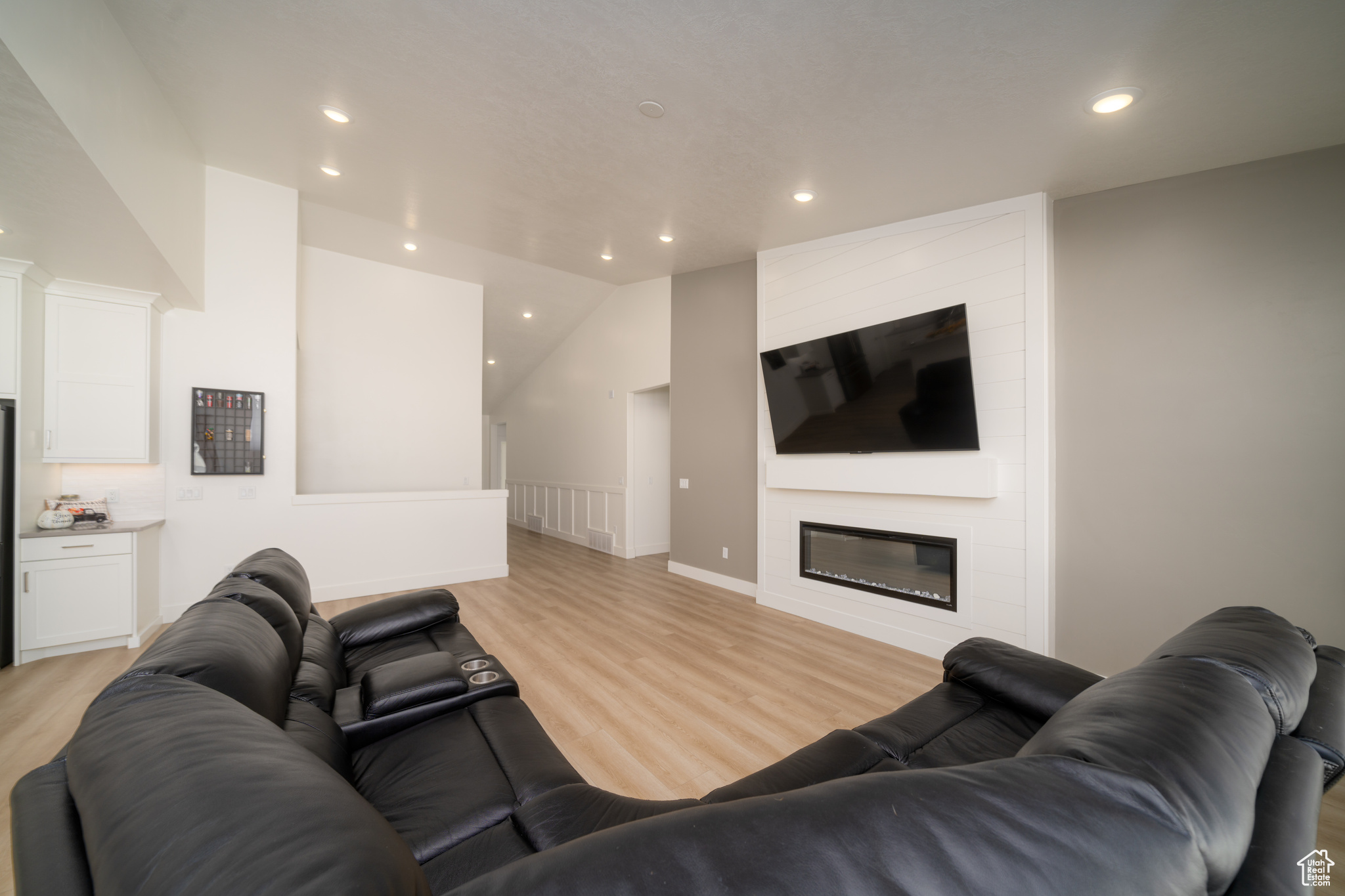 Living room with a fireplace, light hardwood / wood-style flooring, and lofted ceiling