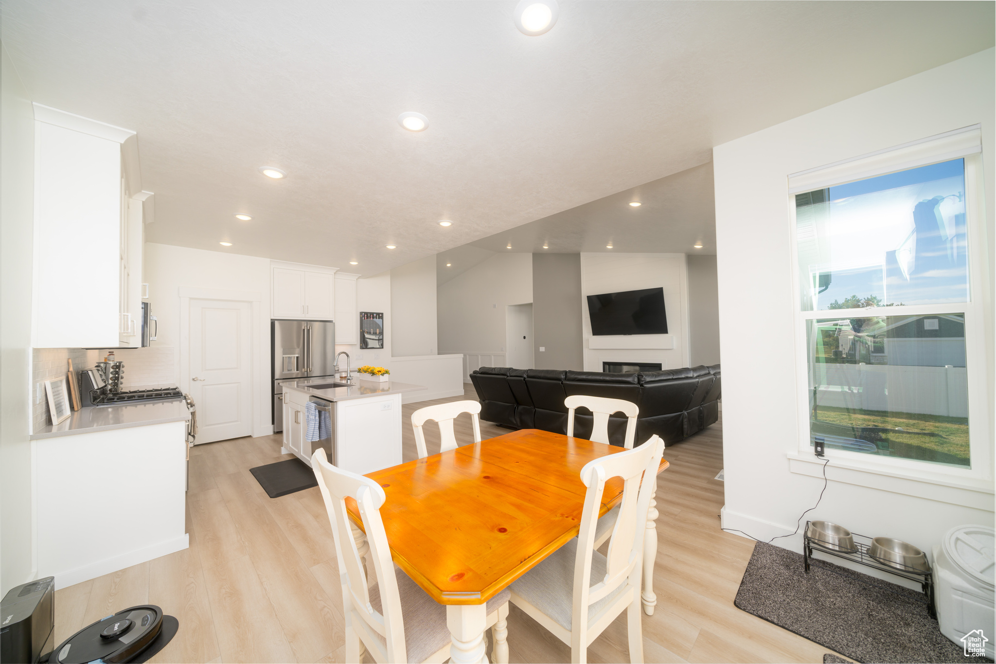 Dining space featuring lofted ceiling, sink, and light hardwood / wood-style flooring