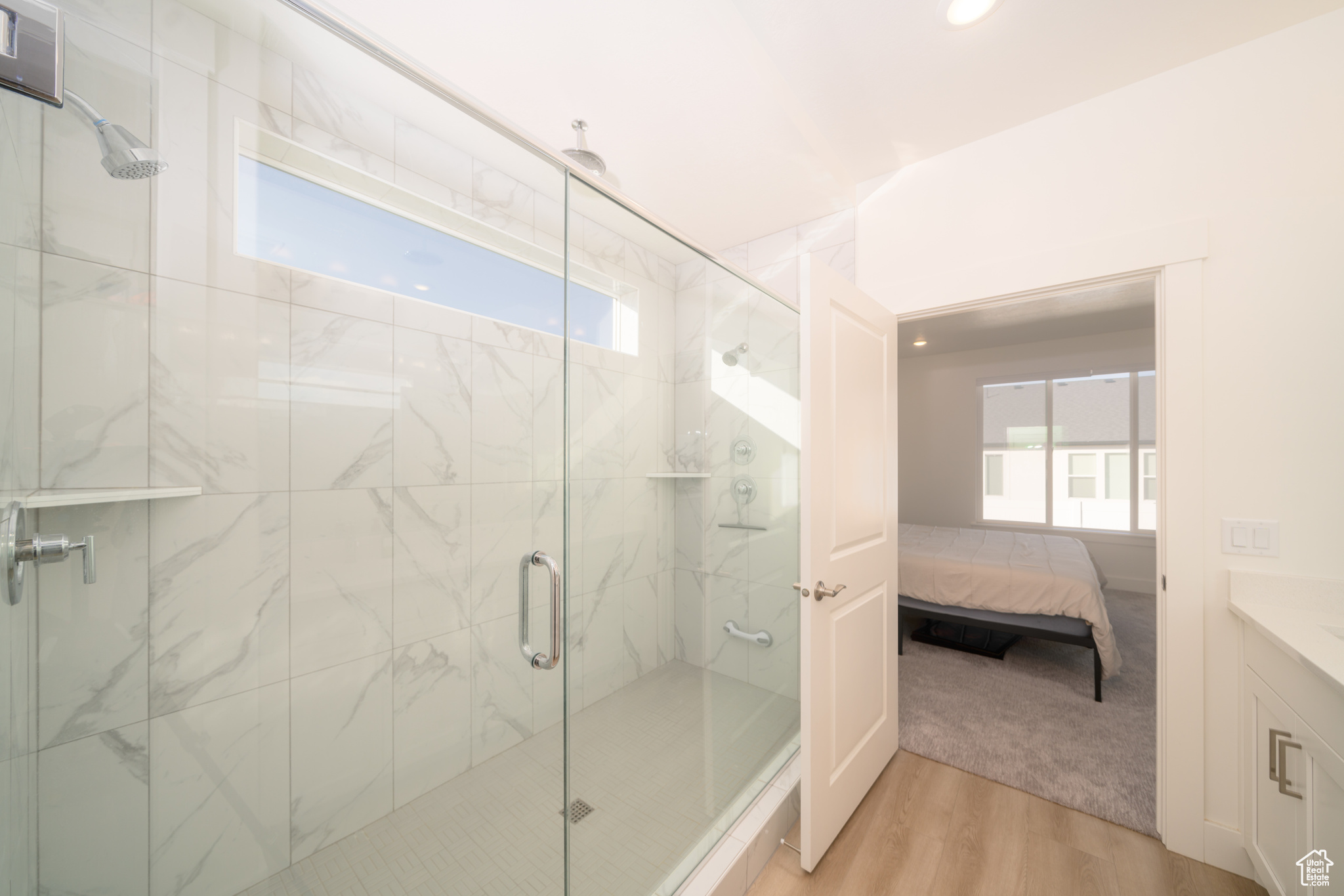 Bathroom with an enclosed shower, wood-type flooring, vanity, and a wealth of natural light