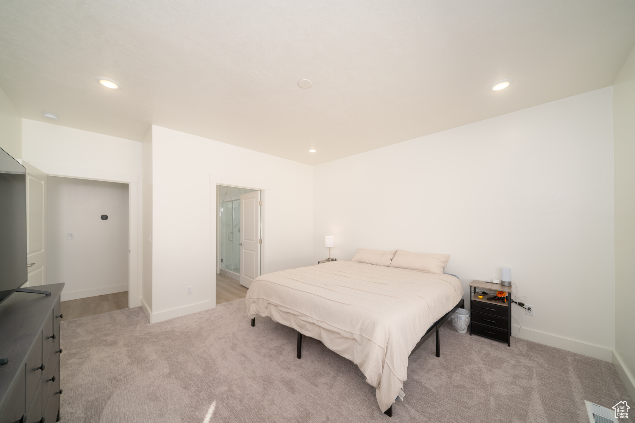 Bedroom featuring ensuite bathroom and light carpet