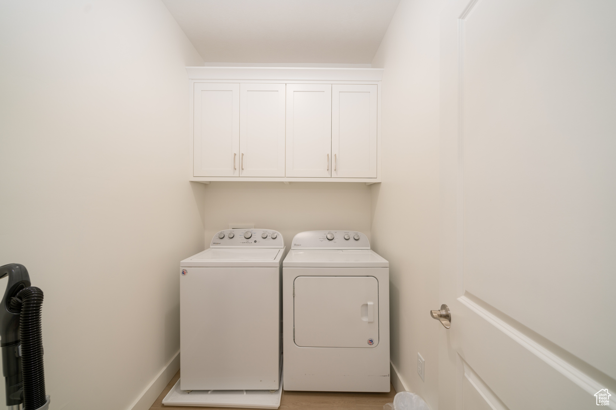 Clothes washing area featuring separate washer and dryer and cabinets