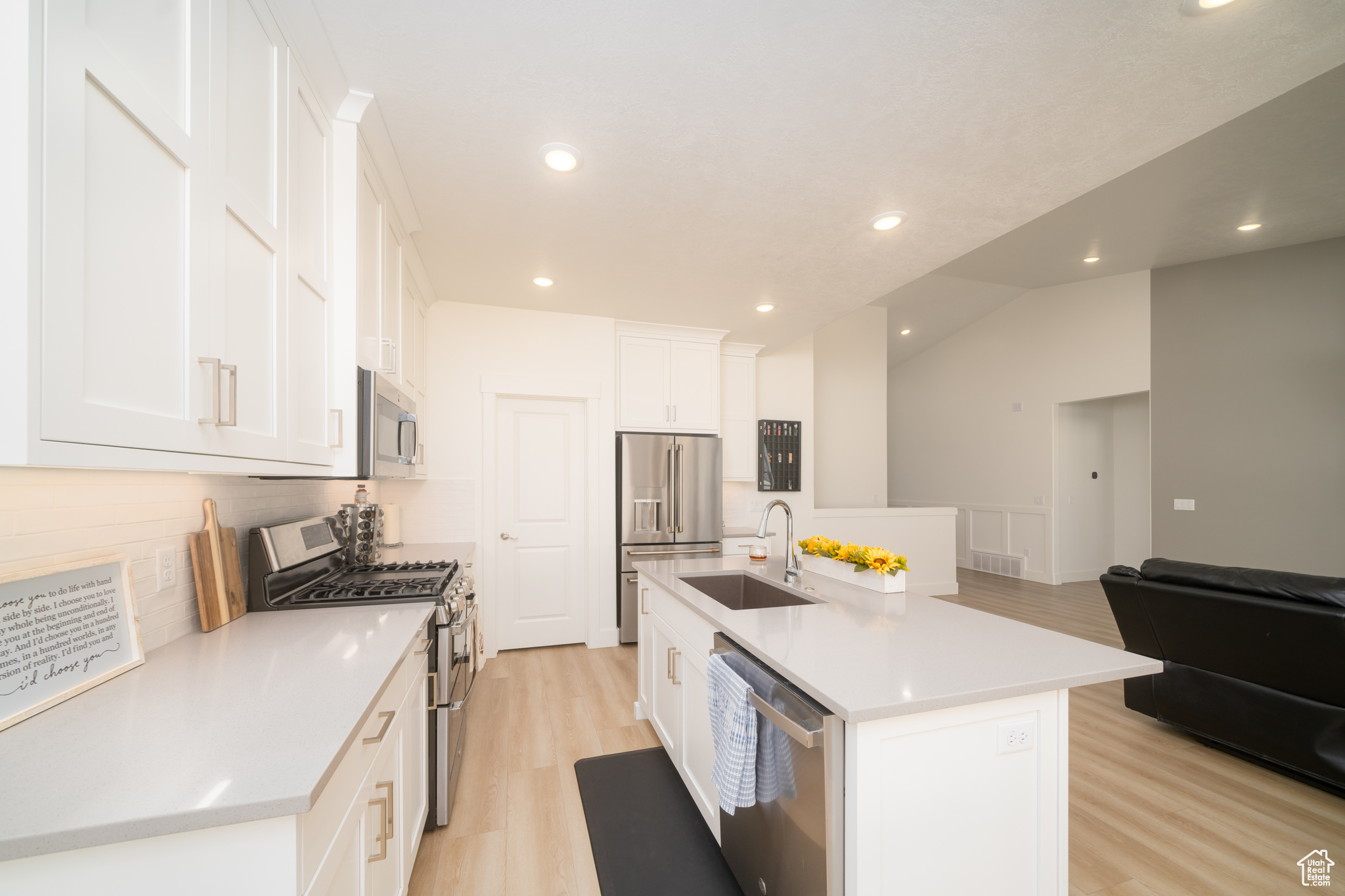 Kitchen featuring white cabinets, sink, an island with sink, and stainless steel appliances