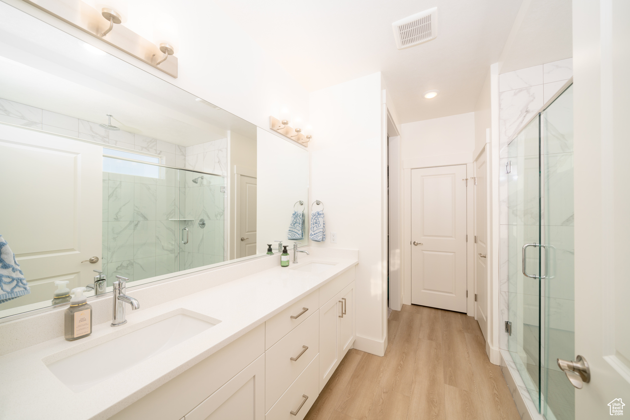 Bathroom featuring vanity, wood-type flooring, and a shower with shower door