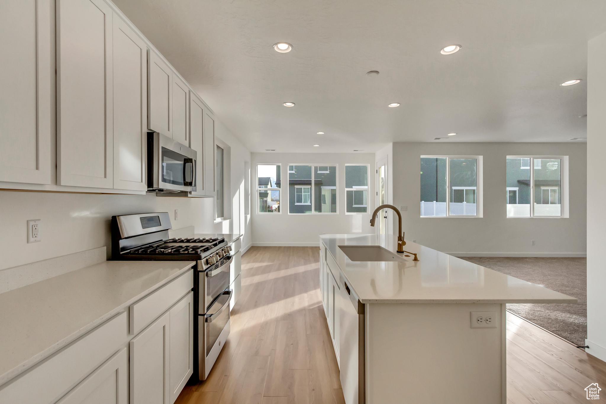 Kitchen featuring sink, light wood-type flooring, stainless steel appliances, and an island with sink