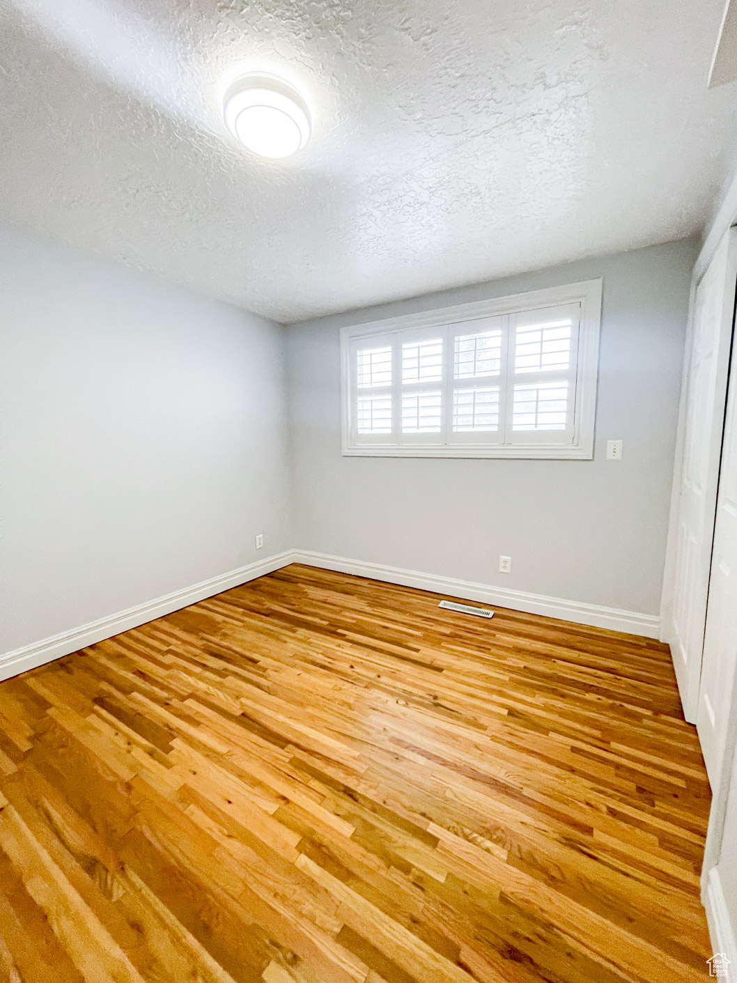 Spare room with light hardwood / wood-style floors and a textured ceiling