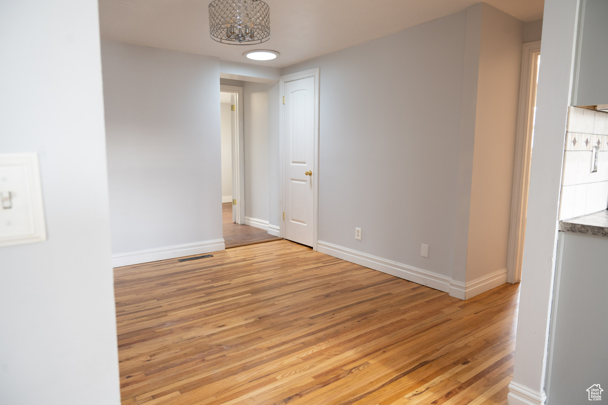 Spare room with light hardwood / wood-style floors and an inviting chandelier