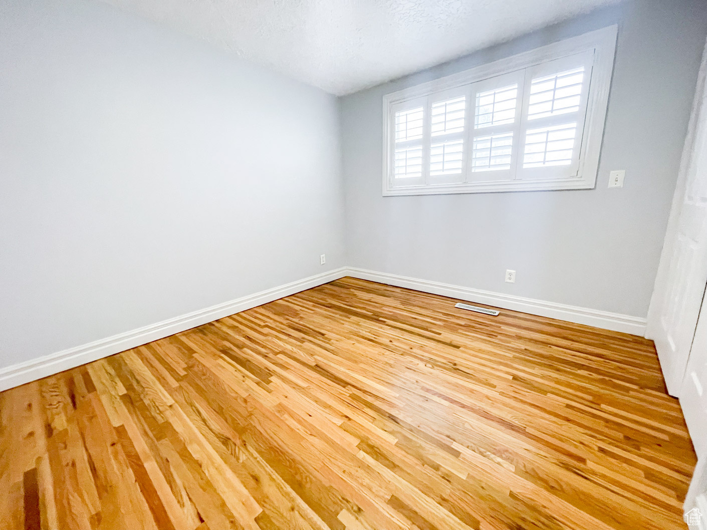 Spare room featuring a textured ceiling and light hardwood / wood-style floors