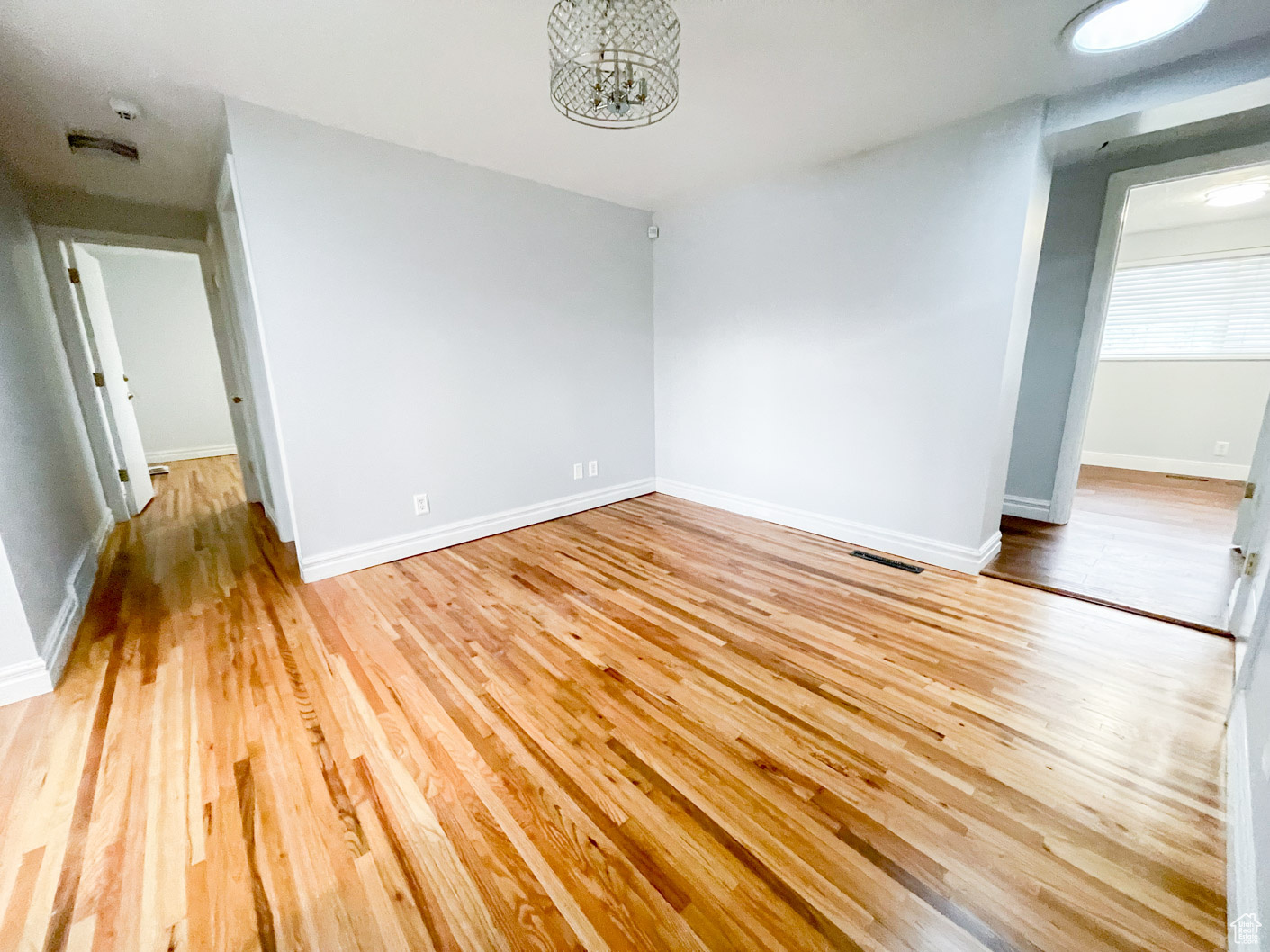 Spare room with a chandelier and light wood-type flooring