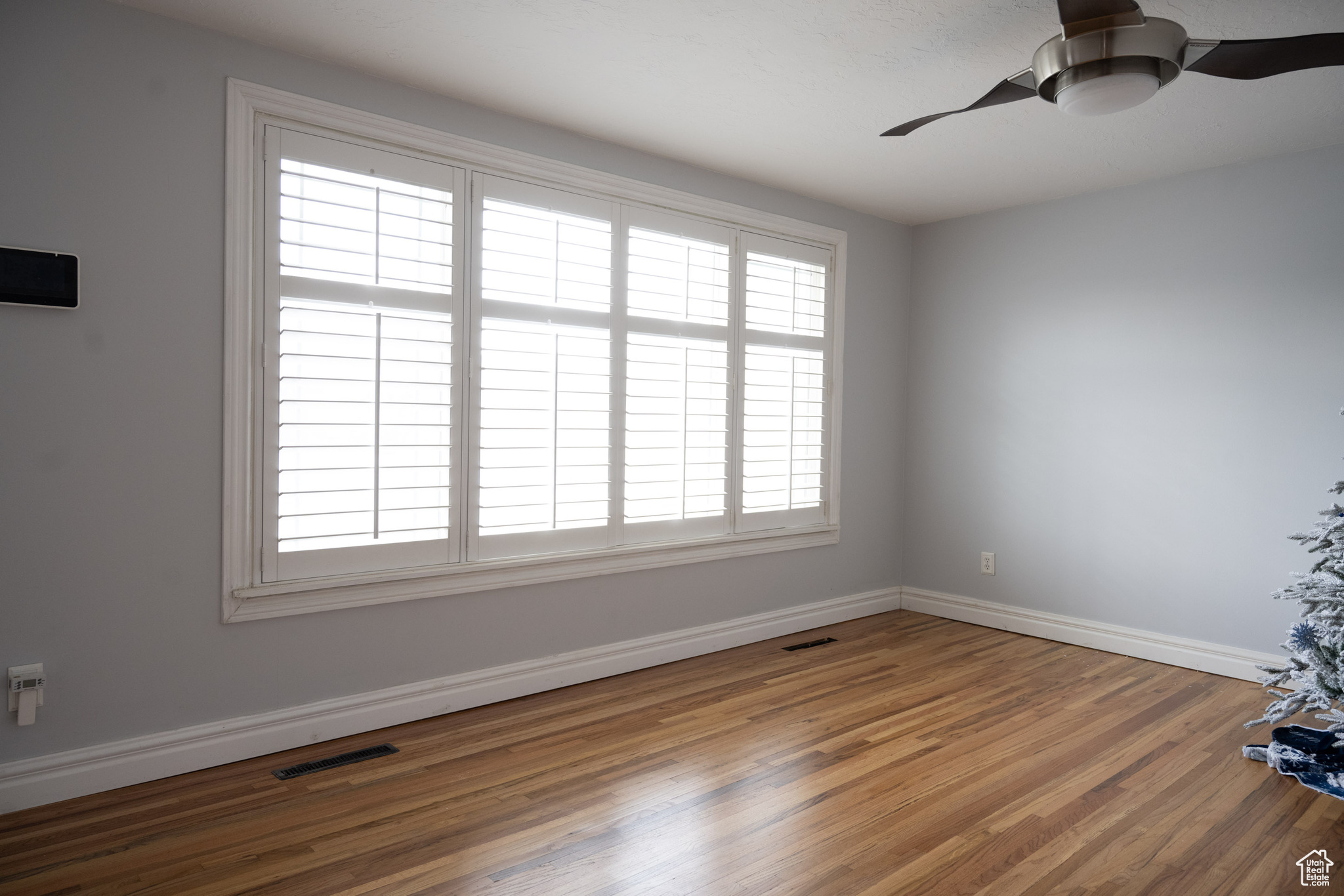 Empty room with ceiling fan and hardwood / wood-style floors