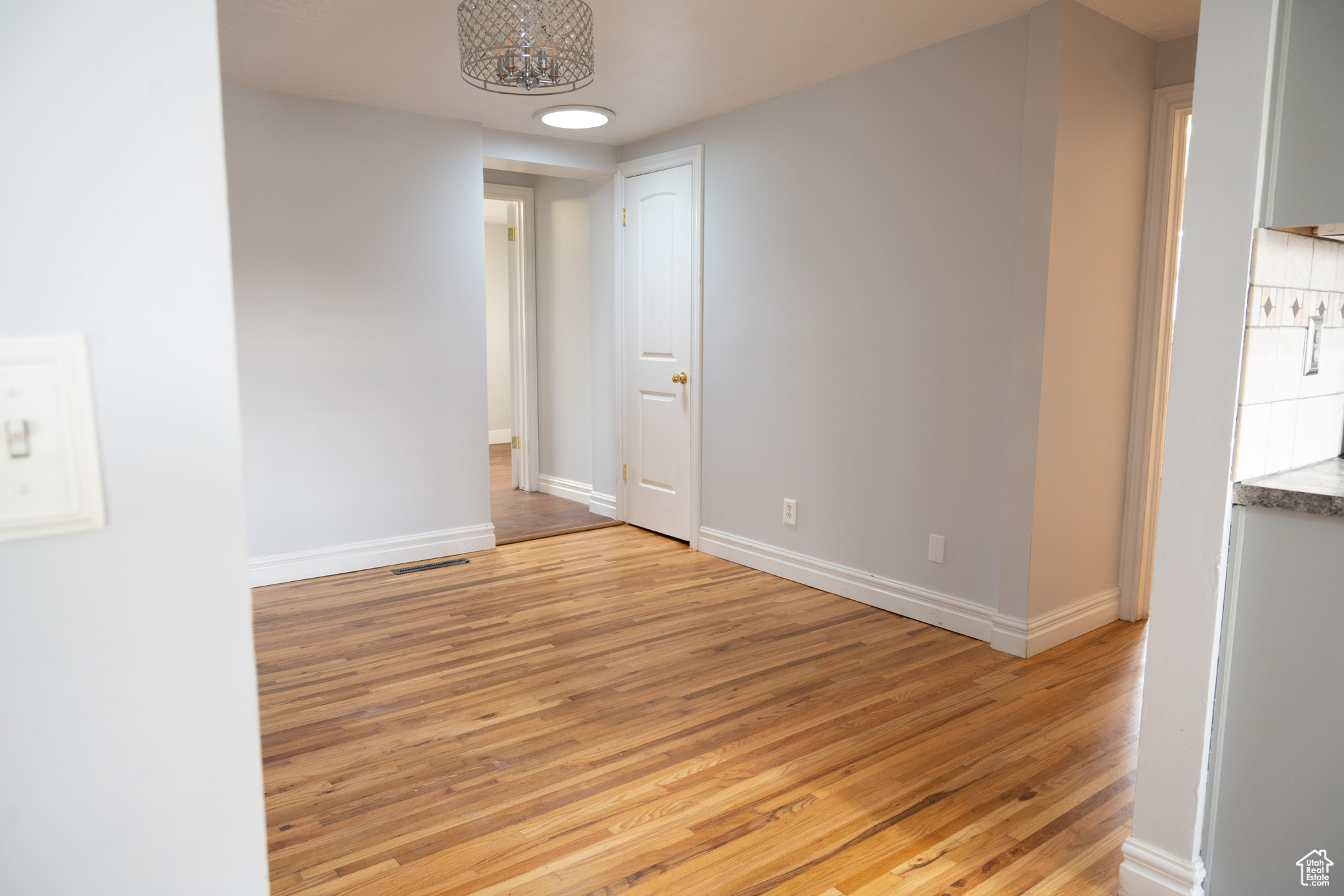 Empty room with a notable chandelier and light hardwood / wood-style floors