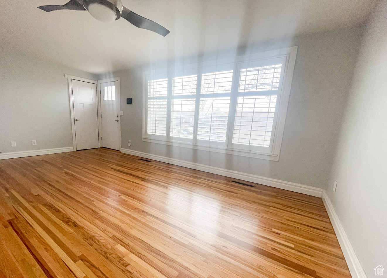 Unfurnished living room featuring ceiling fan and light hardwood / wood-style flooring