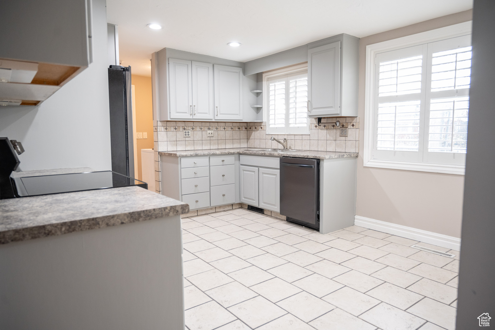 Kitchen featuring black range oven, dishwasher, sink, and tasteful backsplash