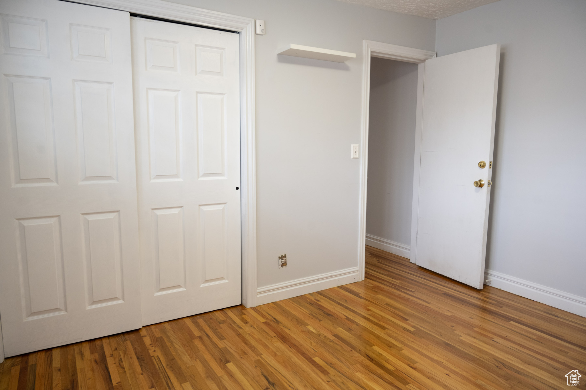 Unfurnished bedroom with a textured ceiling, hardwood / wood-style flooring, and a closet