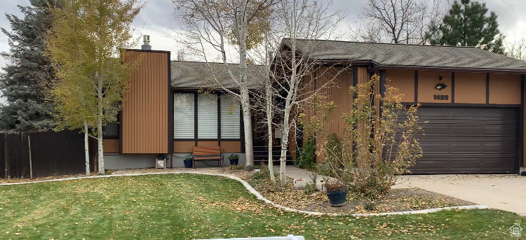 View of front of property featuring a front yard and a garage