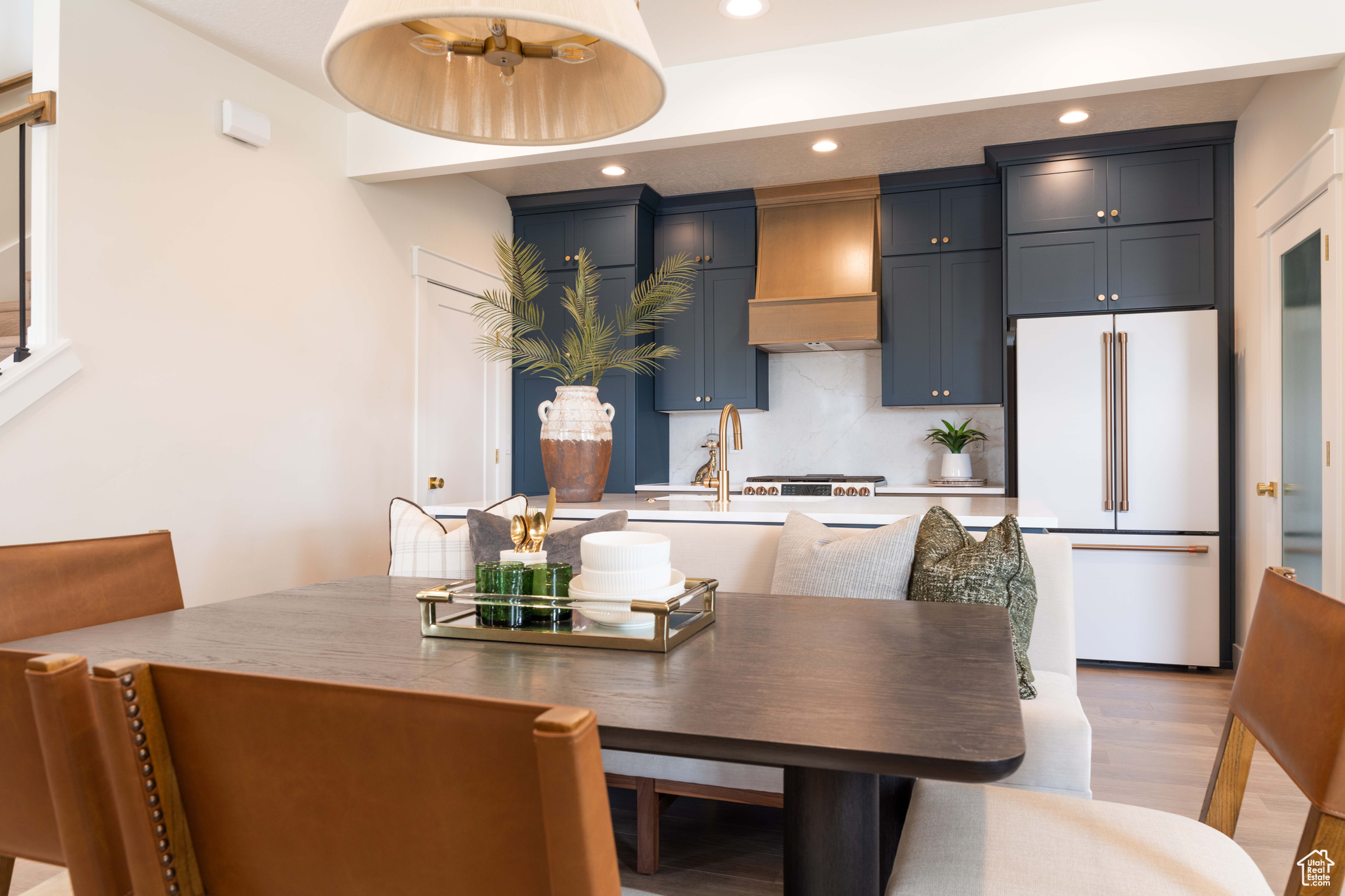 Kitchen featuring backsplash, premium range hood, sink, high end white fridge, and light wood-type flooring