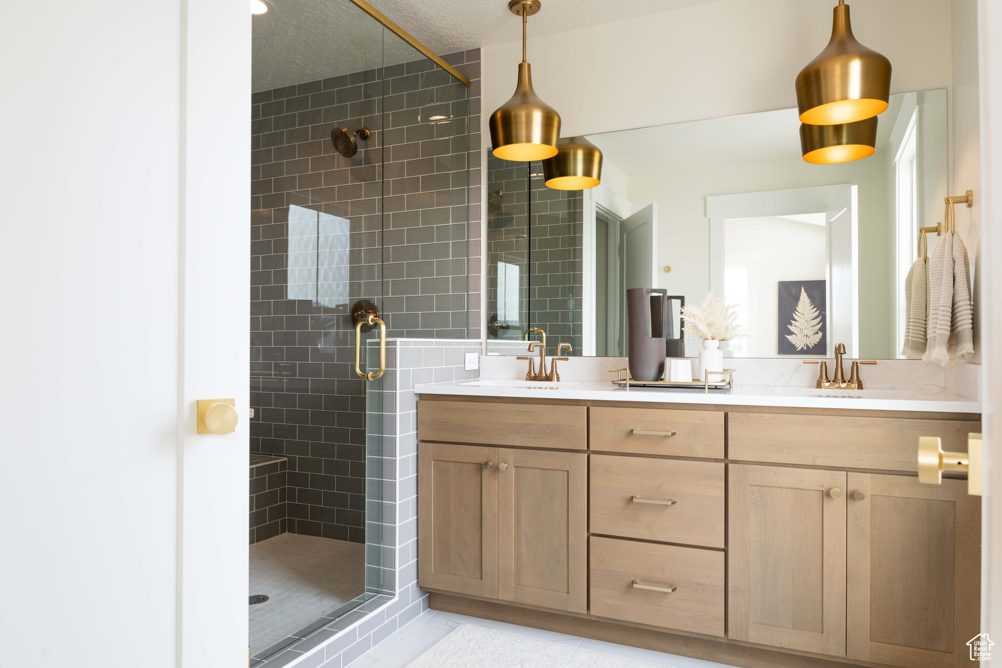 Bathroom featuring tile patterned floors, a shower with door, and vanity