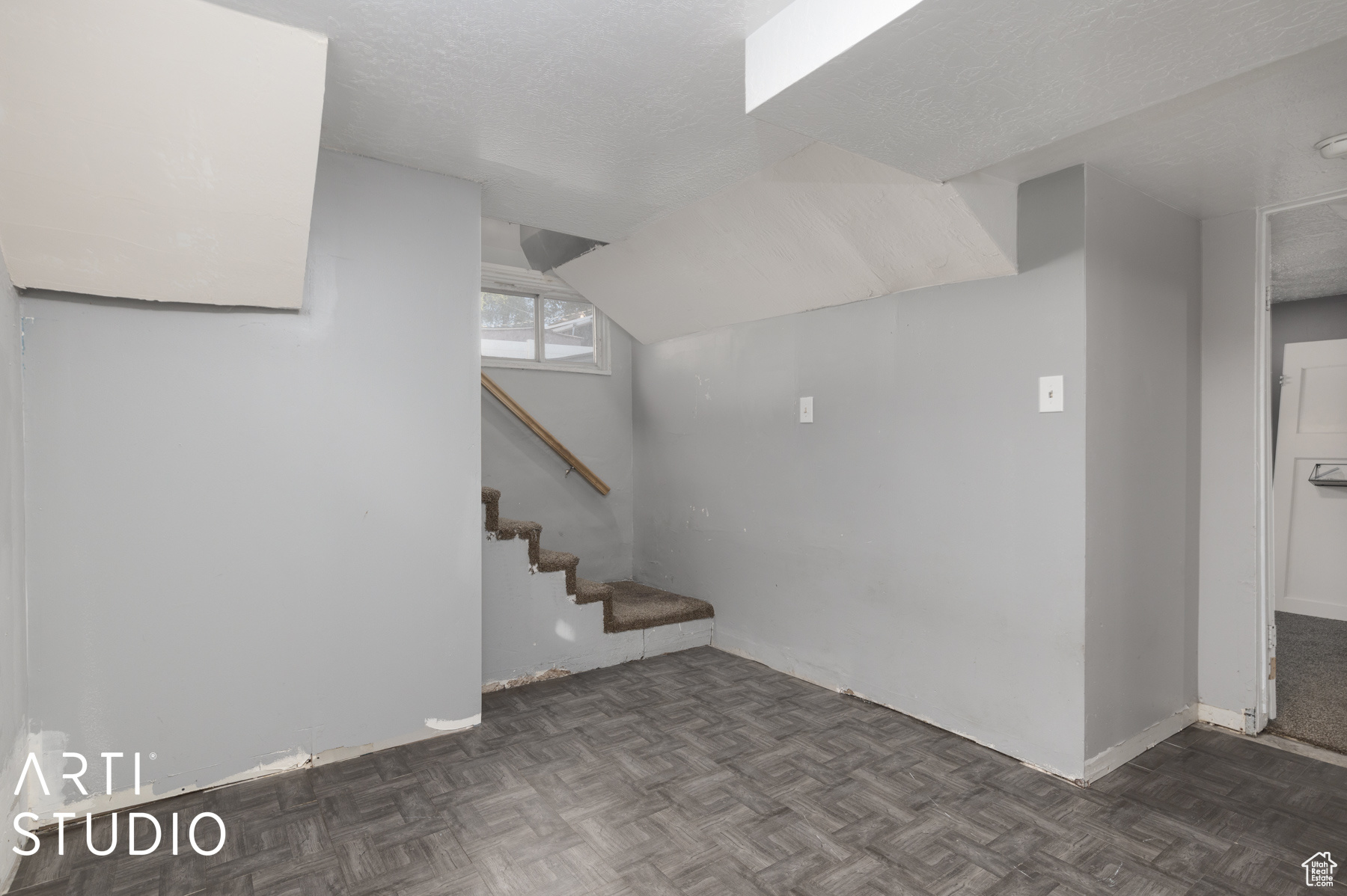 Basement with a textured ceiling and dark parquet floors