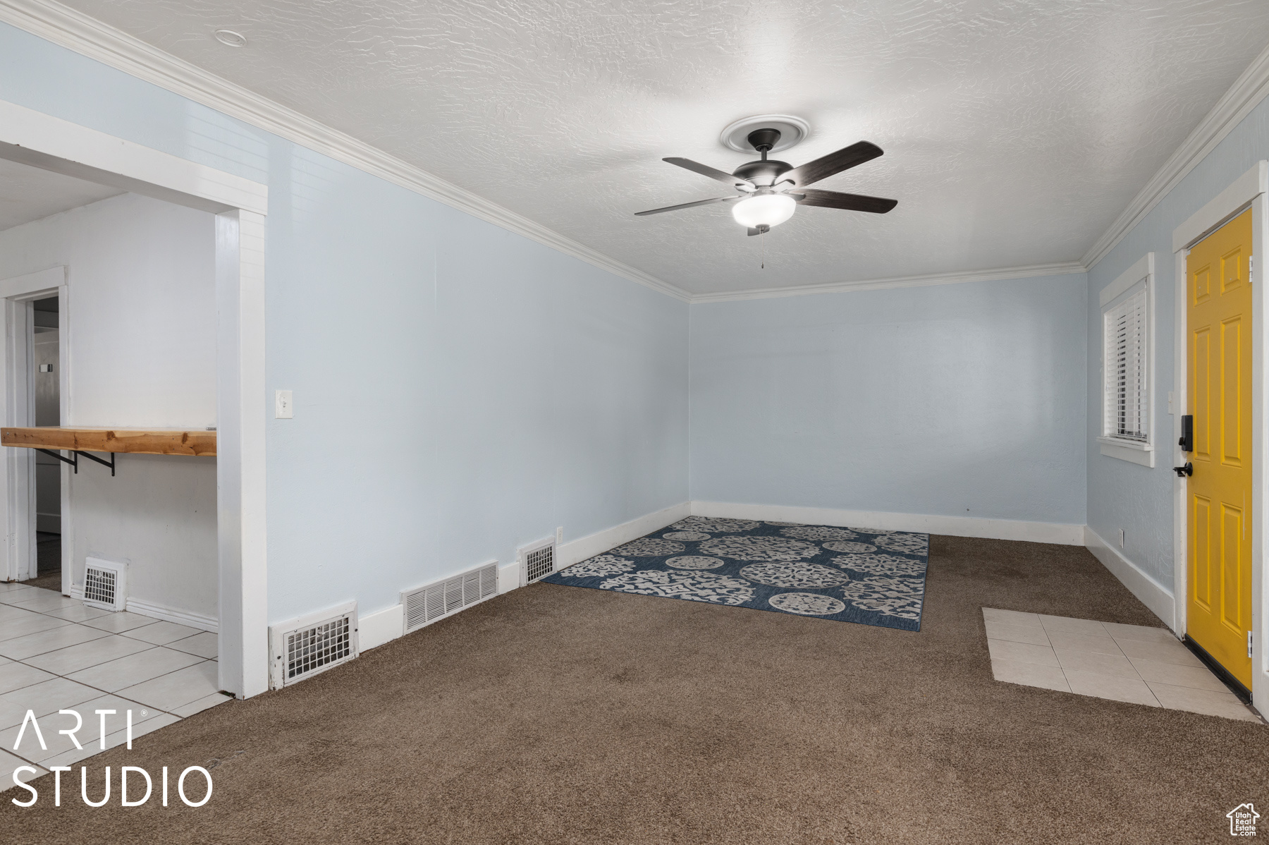 Carpeted empty room featuring a textured ceiling, ceiling fan, and ornamental molding