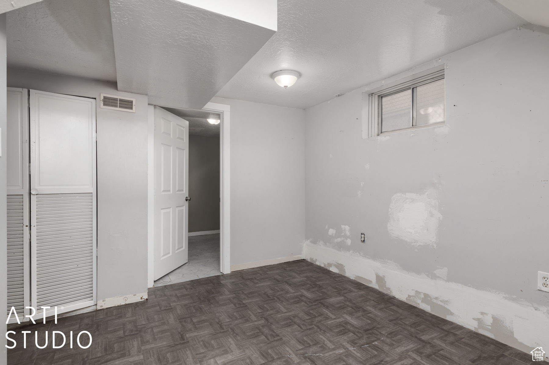 Basement with dark parquet flooring and a textured ceiling