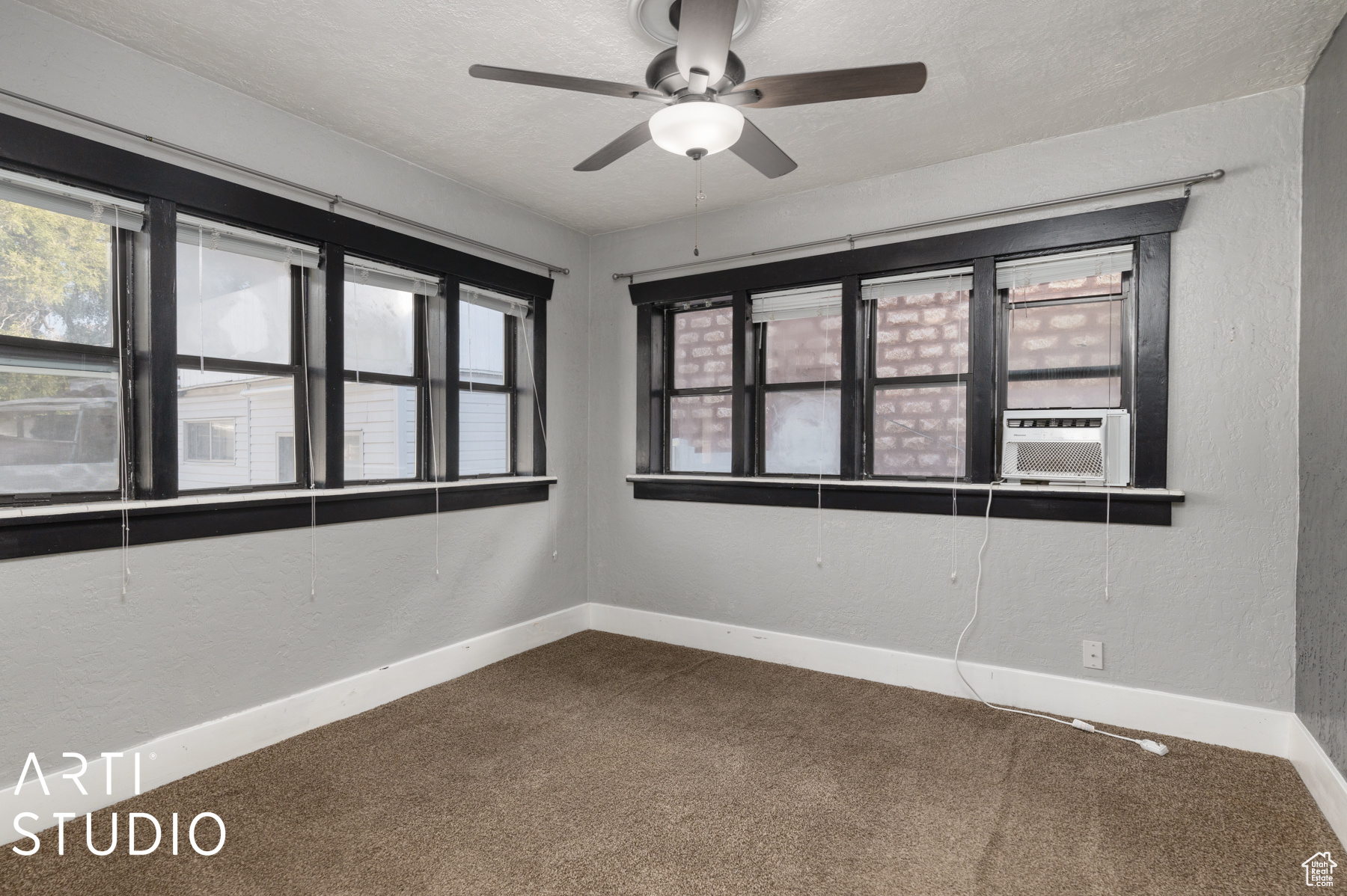 Carpeted spare room with plenty of natural light, ceiling fan, and a textured ceiling