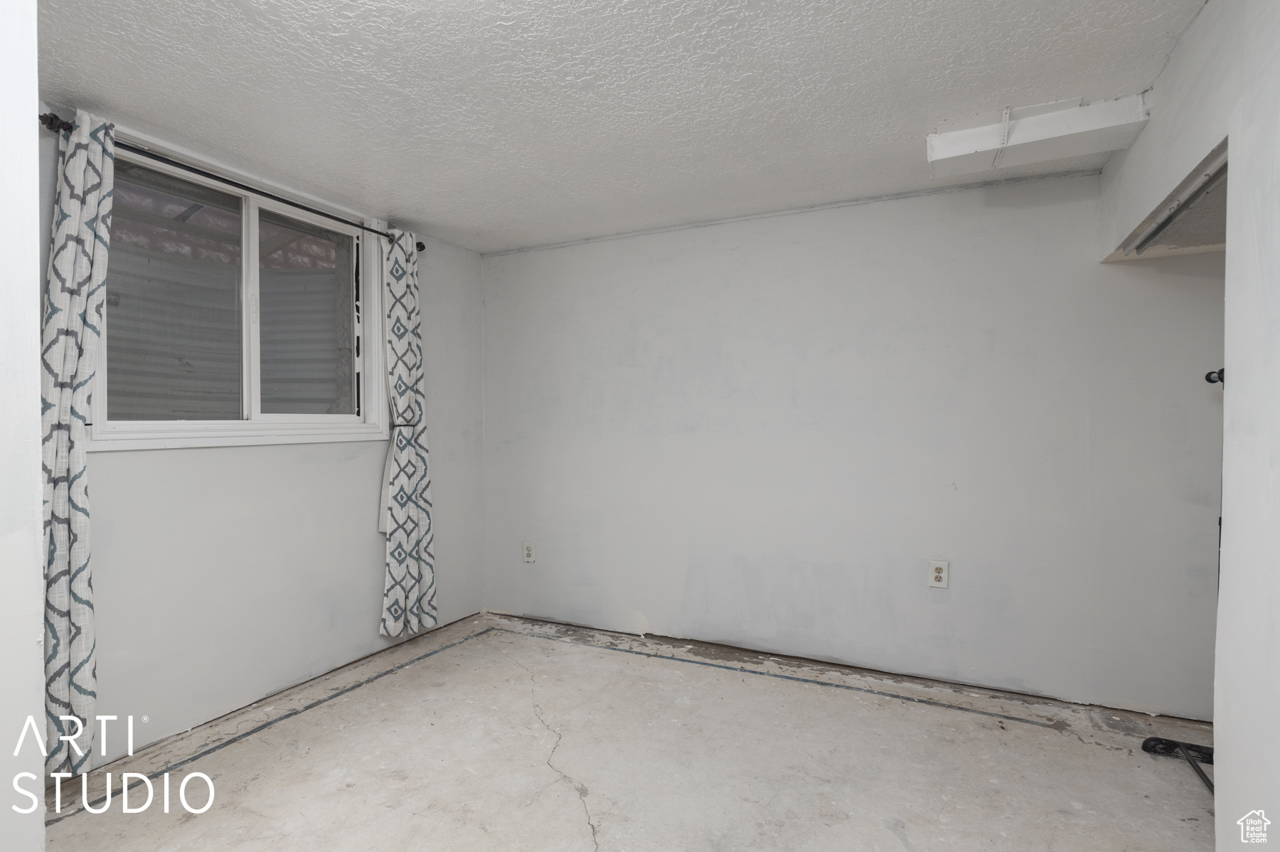 Empty room featuring concrete flooring and a textured ceiling