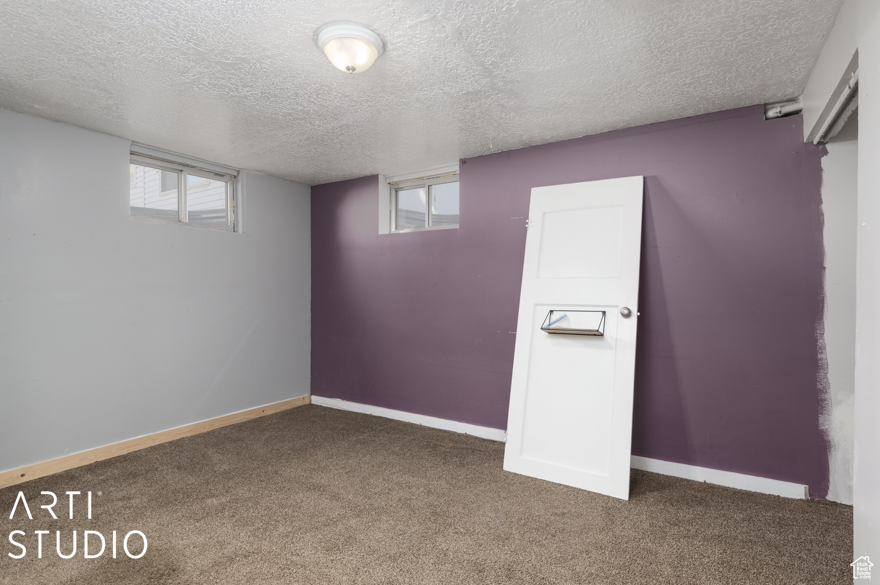 Basement with dark colored carpet and a textured ceiling