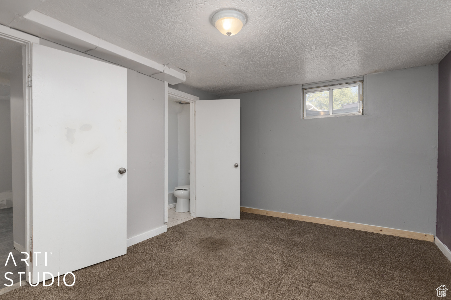 Interior space with connected bathroom, dark carpet, and a textured ceiling