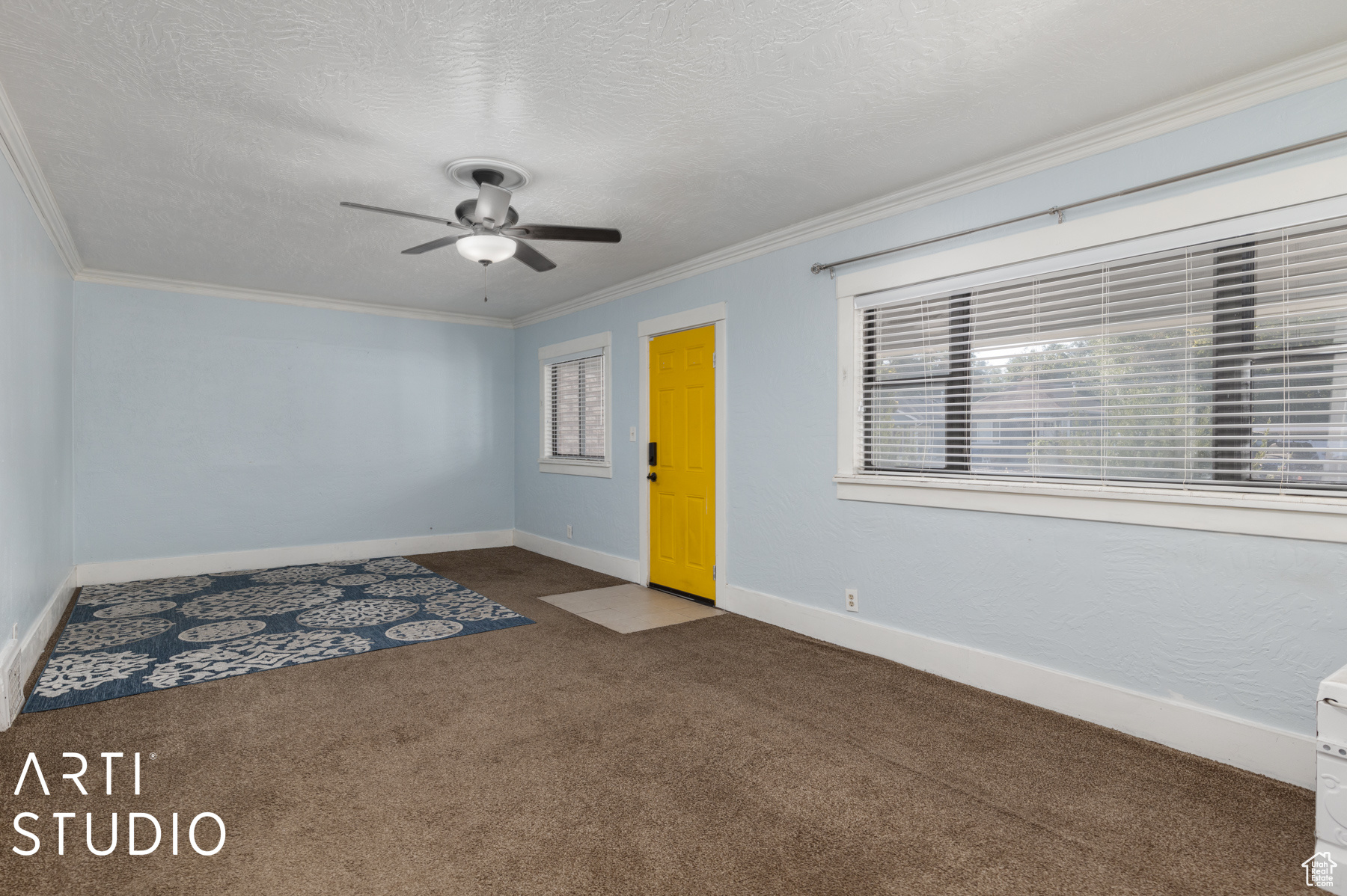 Carpeted empty room featuring a textured ceiling, ceiling fan, and crown molding