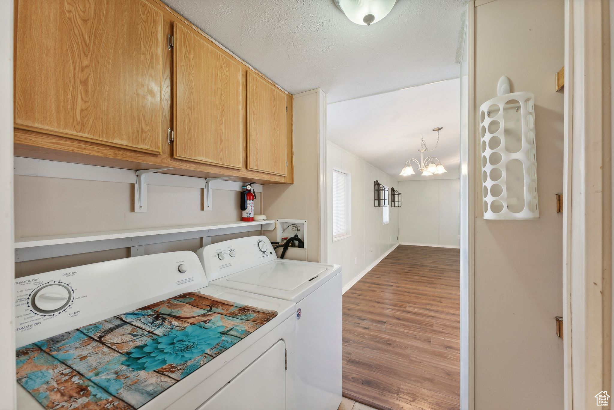 Washroom with cabinets, separate washer and dryer, a notable chandelier, wood-type flooring, and a textured ceiling