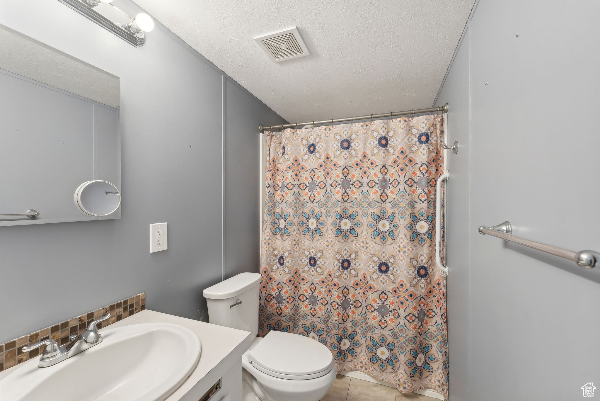 Bathroom with vanity, tile patterned flooring, toilet, a textured ceiling, and tasteful backsplash